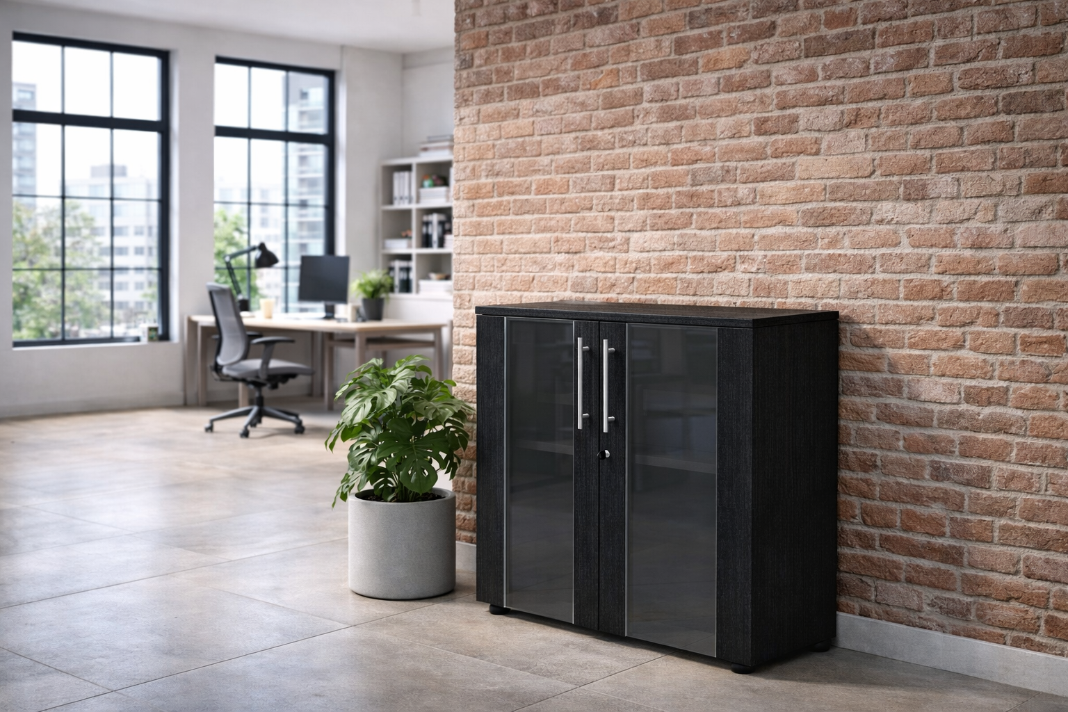 Un bureau moderne avec un mur de briques, de grandes fenêtres, des portes vitrées, une plante en pot, un bureau avec un ordinateur et une chaise, et l'armoire Monsieur Bureau Basse Flora Portes Vitrées H81.4 cm. Design spacieux et lumière naturelle pour un rangement professionnel optimal.