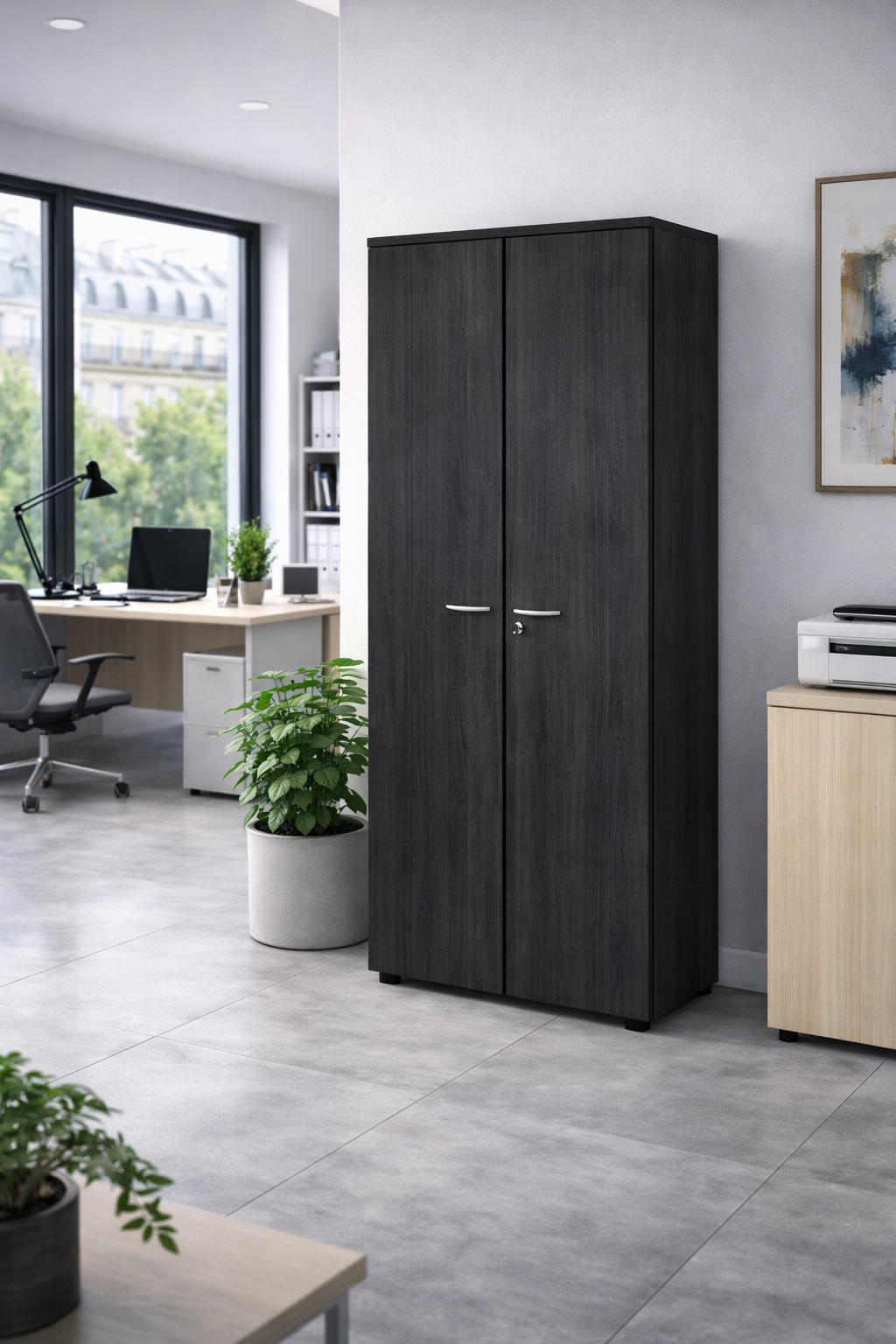 L'Armoire haute H180 Effect et Budget de Monsieur Bureau, avec sa finition en bois foncé et ses poignées argentées, trouve sa place dans un bureau moderne aux murs gris clair, au sol carrelé, aux plantes en pot et à la grande fenêtre donnant sur les immeubles de la ville.#finitions_frene_noir