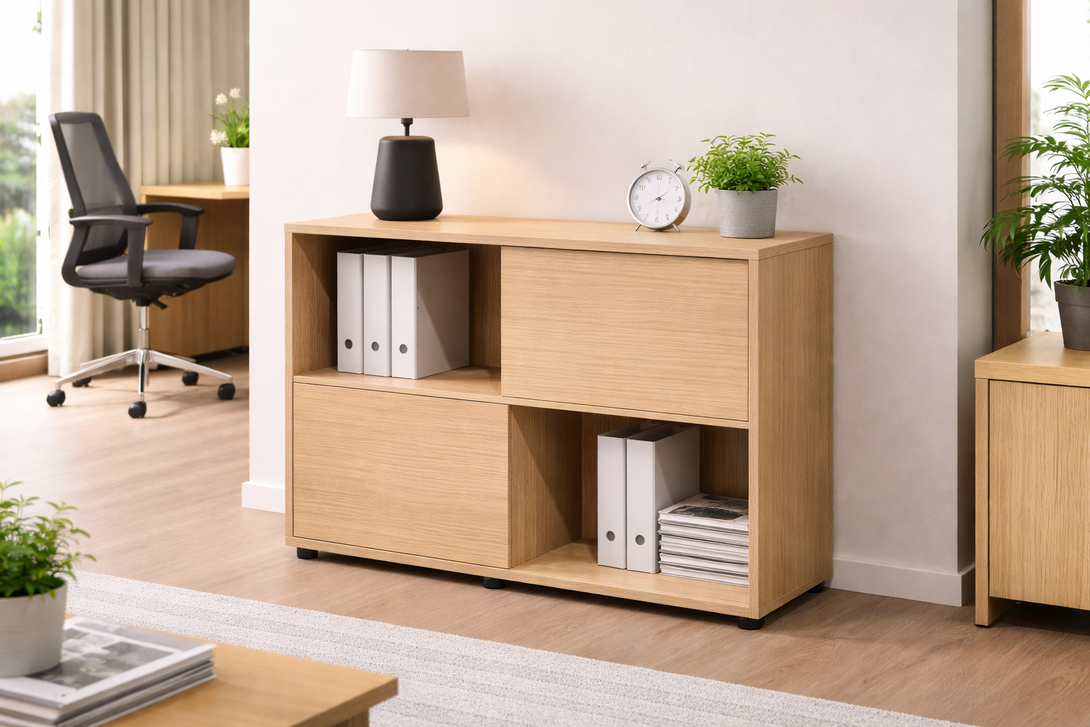 Un bureau moderne présente un Monsieur Bureau Bibliothèque Basse Curvy/Express+ 2 Portes 2 Niches avec des étagères contenant des classeurs blancs, une horloge, une lampe et des plantes en pot. En arrière-plan se trouvent une chaise de bureau et une grande fenêtre à rideaux.#combo_corps_chene_porte_chene