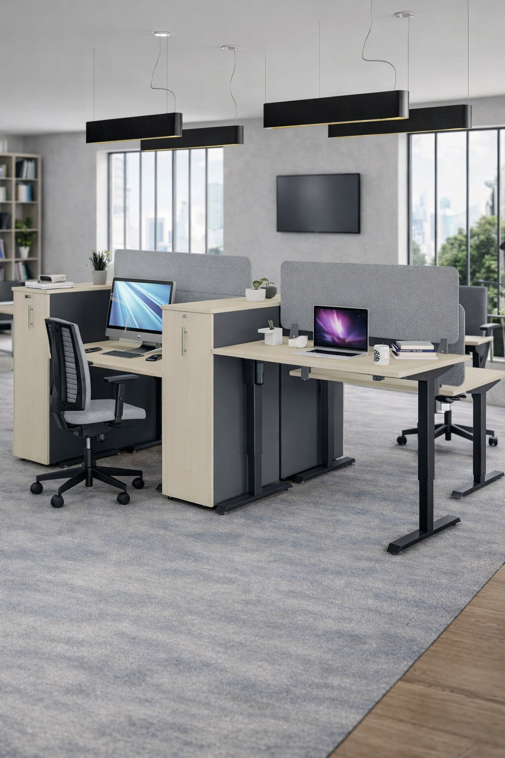 Espace de bureau moderne comprenant deux postes de travail Monsieur Bureau Bureau Électrique Assis-Debout Pro ECO-UP avec chaises, ordinateurs, fournitures et écrans de séparation. De grandes fenêtres offrent une lumière naturelle et une vue sur la ville.
