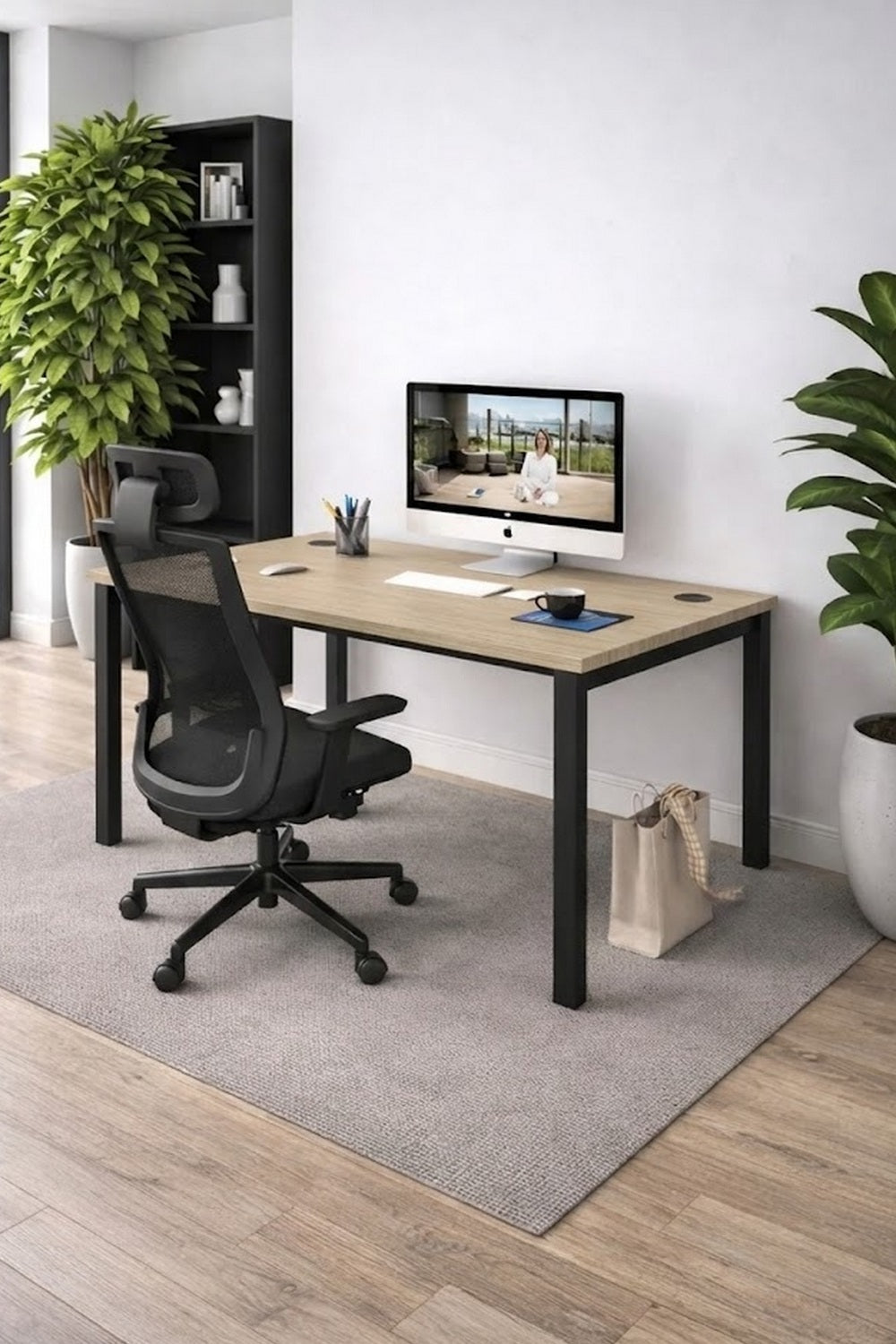 Un espace de travail moderne avec le Bureau individuel Astral Profondeur 70 ou 80 de Monsieur Bureau, associé à une chaise de bureau noire, un ordinateur de bureau, des cahiers et des plantes en pot sur une moquette claire avec des planchers en bois et une étagère derrière.#combo_chene_fil_noir