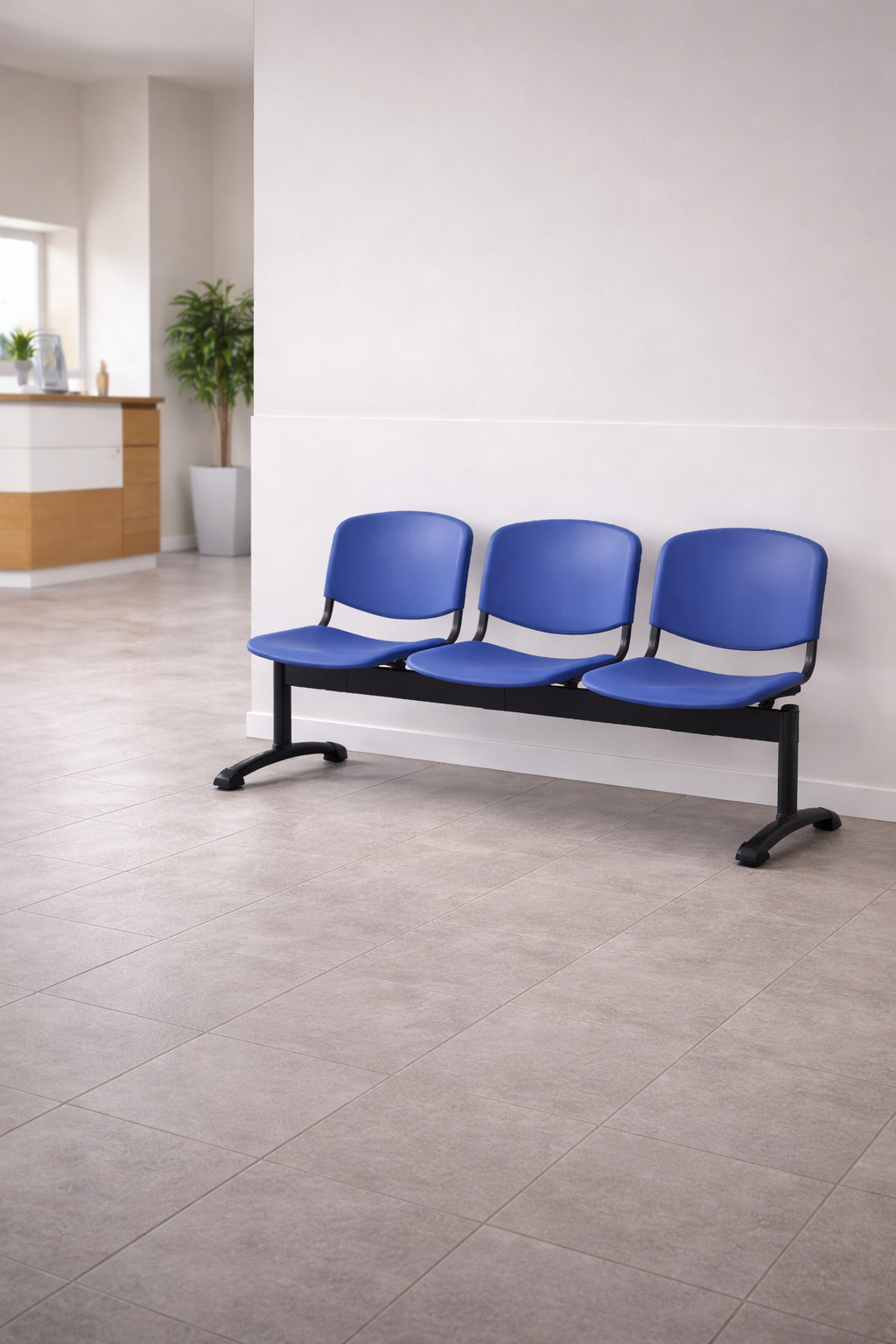Trois places bleues Sièges sur Poutre INO-P 3 de Monsieur Bureau, avec des pieds en métal noir, sont alignées contre un mur blanc dans une salle d'attente lumineuse avec des sols carrelés et une plante en pot.#combo_3_places_bleu