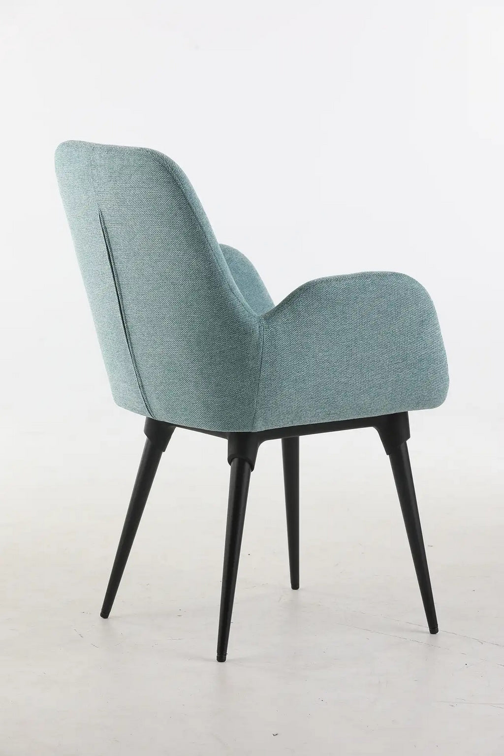 Le Fauteuil d'accueil et réunion Shino de Monsieur Bureau se caractérise par un revêtement bleu clair, un dossier incurvé et des pieds en métal noir, le tout sur un fond blanc uni.