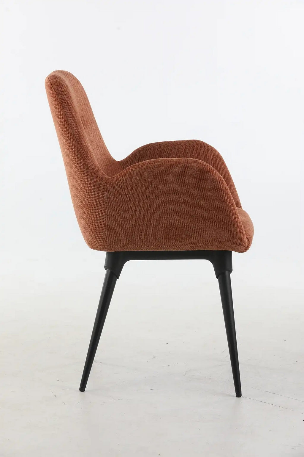 Vue latérale du Fauteuil d'accueil et réunion Shino - Pieds métal de Monsieur Bureau, un fauteuil moderne avec un revêtement courbé de couleur rouille et des pieds épurés en métal noir, sur un fond blanc uni.