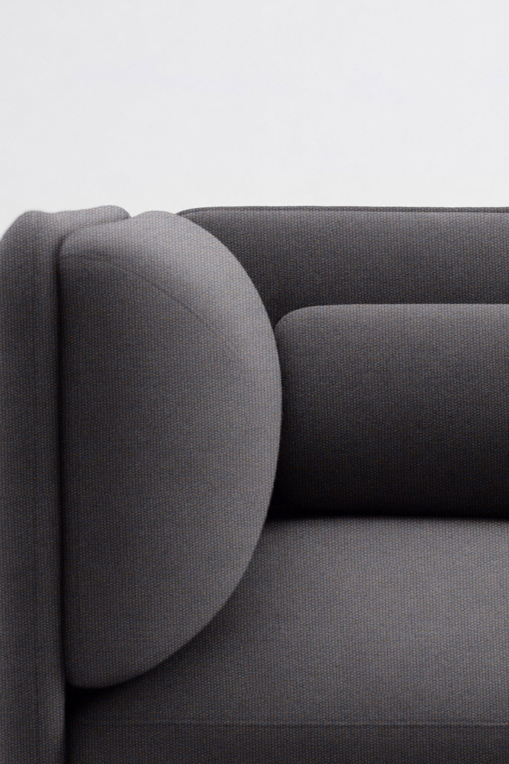 Gros plan sur le côté gauche du Fauteuil d'accueil modulaire Aurea de Monsieur Bureau, qui présente un design moderne gris foncé avec des accoudoirs et des coussins arrondis sur un fond blanc uni.~finitions_gris445