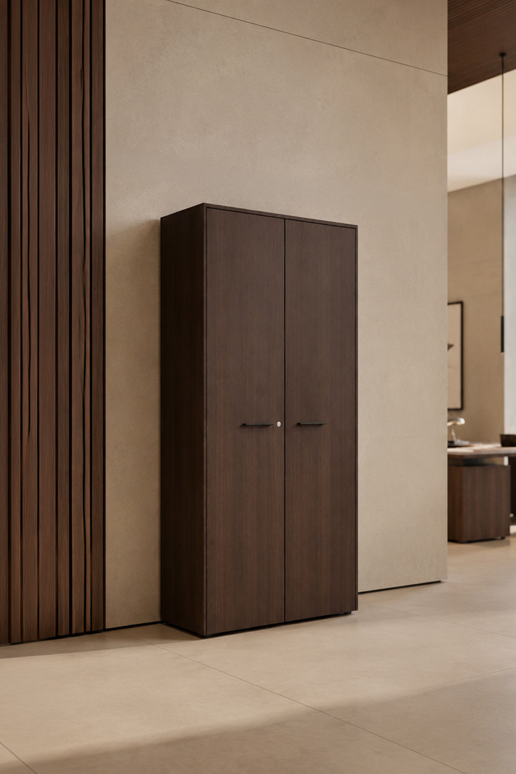 L'Armoire haute Passe Partout 2 portes de Monsieur Bureau (L90 x H195) se détache sur un mur beige clair, apportant une élégance fonctionnelle et un style moderne à cet intérieur minimaliste.#finitions_noyer