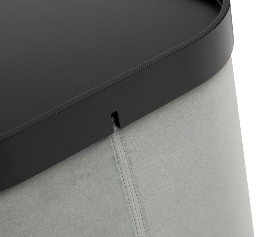 Gros plan sur le "Pouf d'accueil Nordic avec plateau" de Monsieur Bureau, conçu par Busk+Hertzog, composé d'un corps rembourré gris clair et d'un couvercle amovible noir lisse doté d'une encoche pour le soulever facilement.