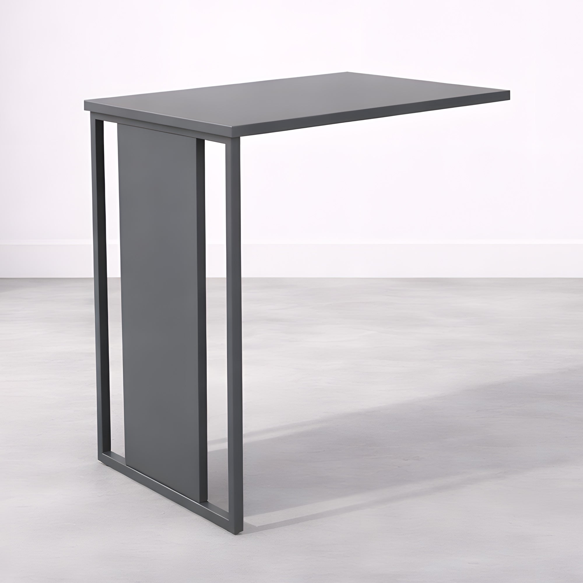 Le Bureau Edge Modulable P80 droit ou angle de Monsieur Bureau se caractérise par un plateau rectangulaire gris foncé et un cadre métallique épuré, incarnant le minimalisme moderne d'inspiration italienne, présenté sur un sol gris clair et un mur pâle.#combo_anthracite_anthracite_mat_retour_seul