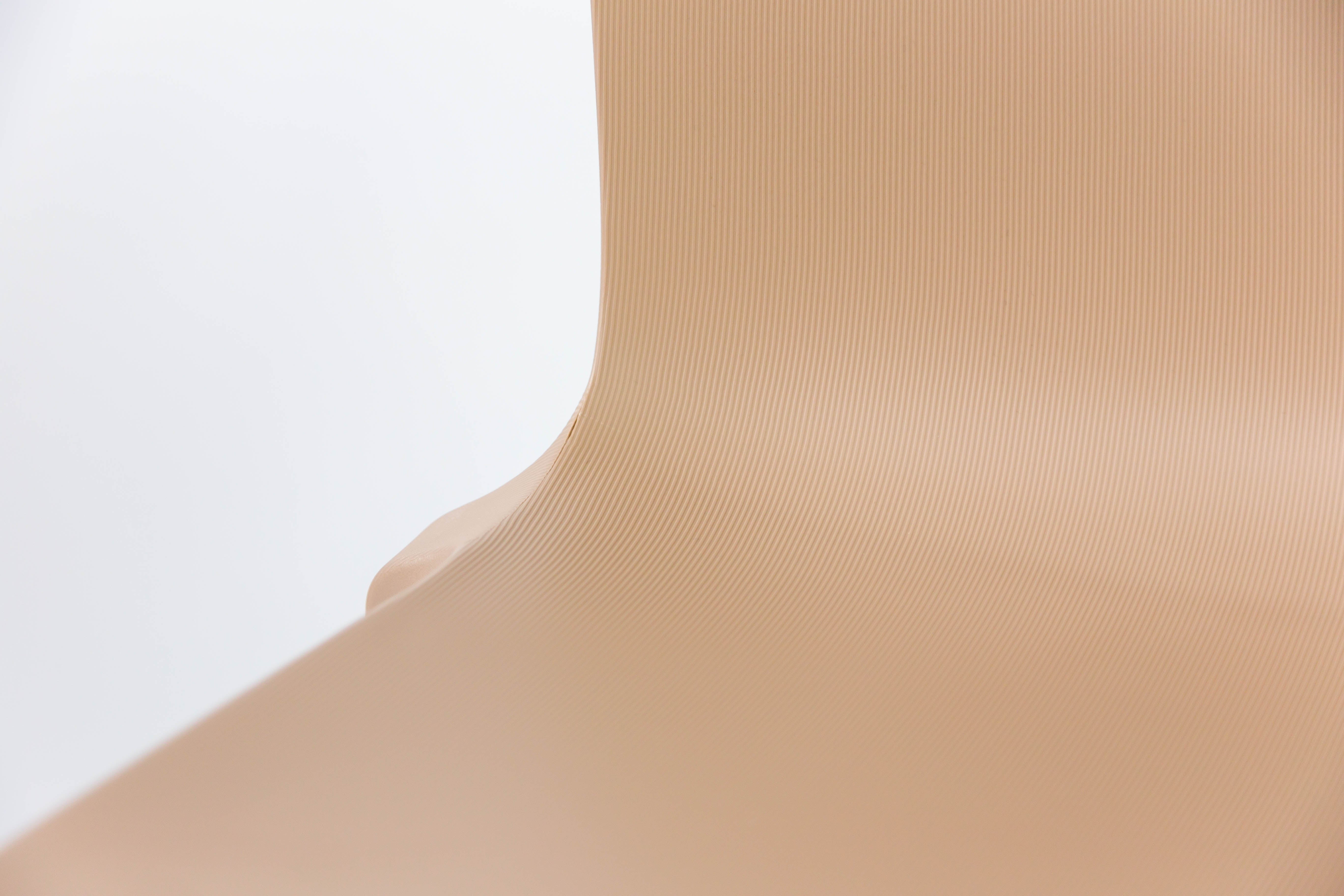 Gros plan sur la surface lisse et incurvée du monobloc en polypropylène beige de la Chaise Extérieur Indi Bellini Empilable de Monsieur Bureau, qui présente de fines lignes verticales sur un fond blanc uni pour un aspect minimaliste et abstrait.