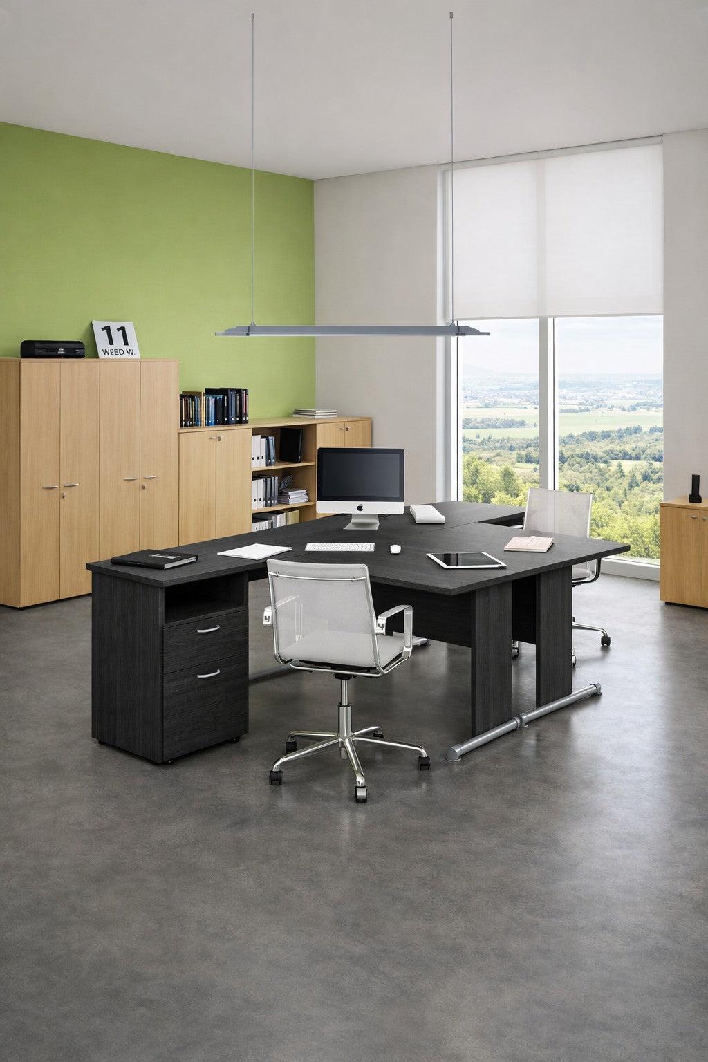 Un bureau moderne présente la Solution de Bureau Compact Budget pieds L de Monsieur Bureau, associée à des chaises blanches, des armoires en bois et des étagères. Des ordinateurs et des fournitures sont posés sur le bureau. De grandes fenêtres laissent entrevoir de la verdure ; les murs sont verts et blancs.