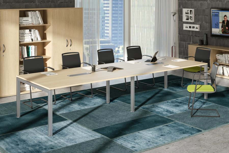 Une salle de conférence moderne avec la Solution de Table 6 pers & Extensions Express+ de Monsieur Bureau, six chaises noires, une chaise verte, des étagères ouvertes, de grandes fenêtres avec vue sur la ville et un tapis à motifs bleus recouvrant le sol.