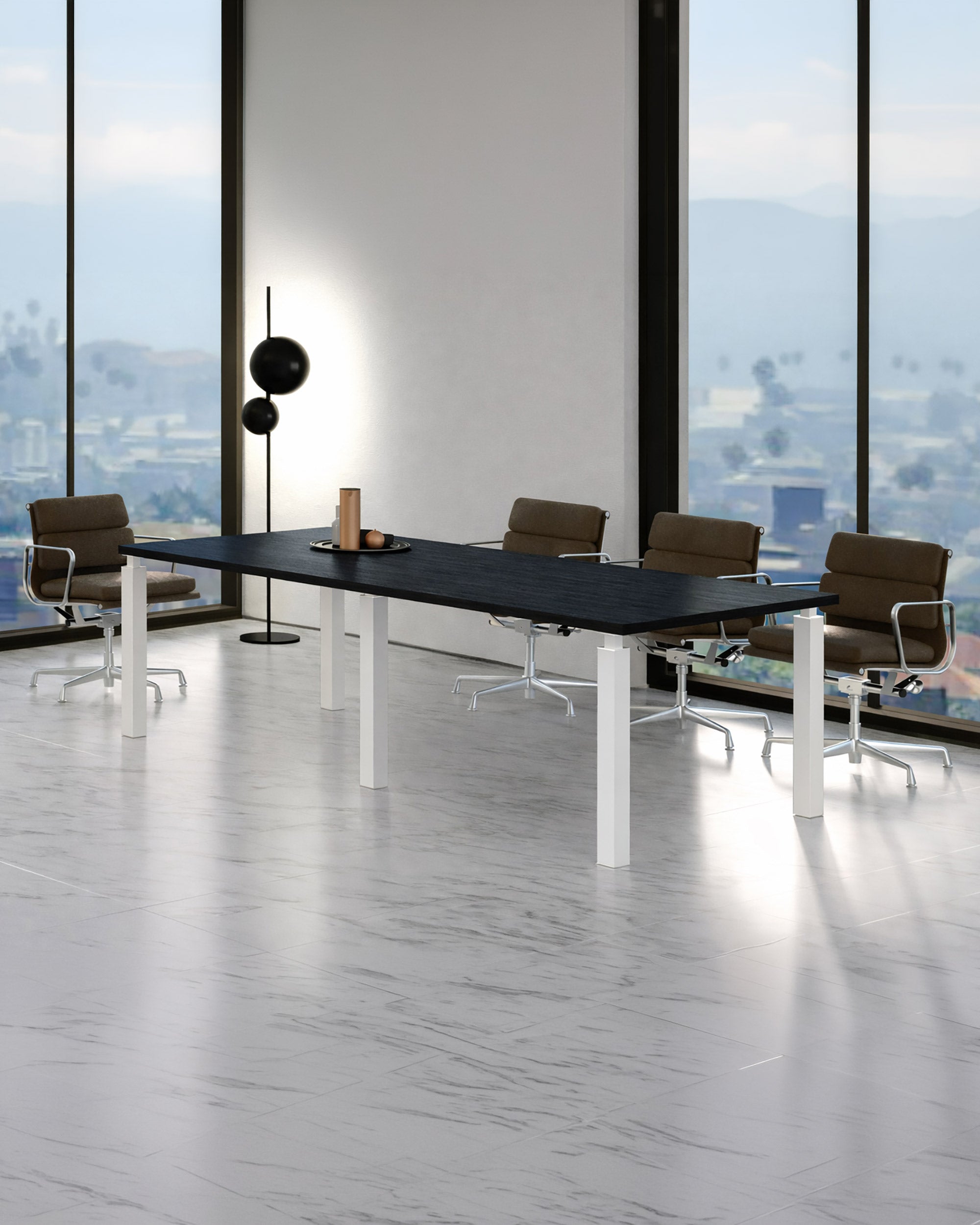Une salle de conférence moderne est équipée d'une Table de Réunion Design Quatro 220 x 100 cm de Monsieur Bureau, de quatre chaises de bureau brunes à roulettes, d'un lampadaire et de grandes fenêtres offrant une vue sur la ville et les montagnes sur un sol en marbre blanc.#combo_frene_noir_blanc