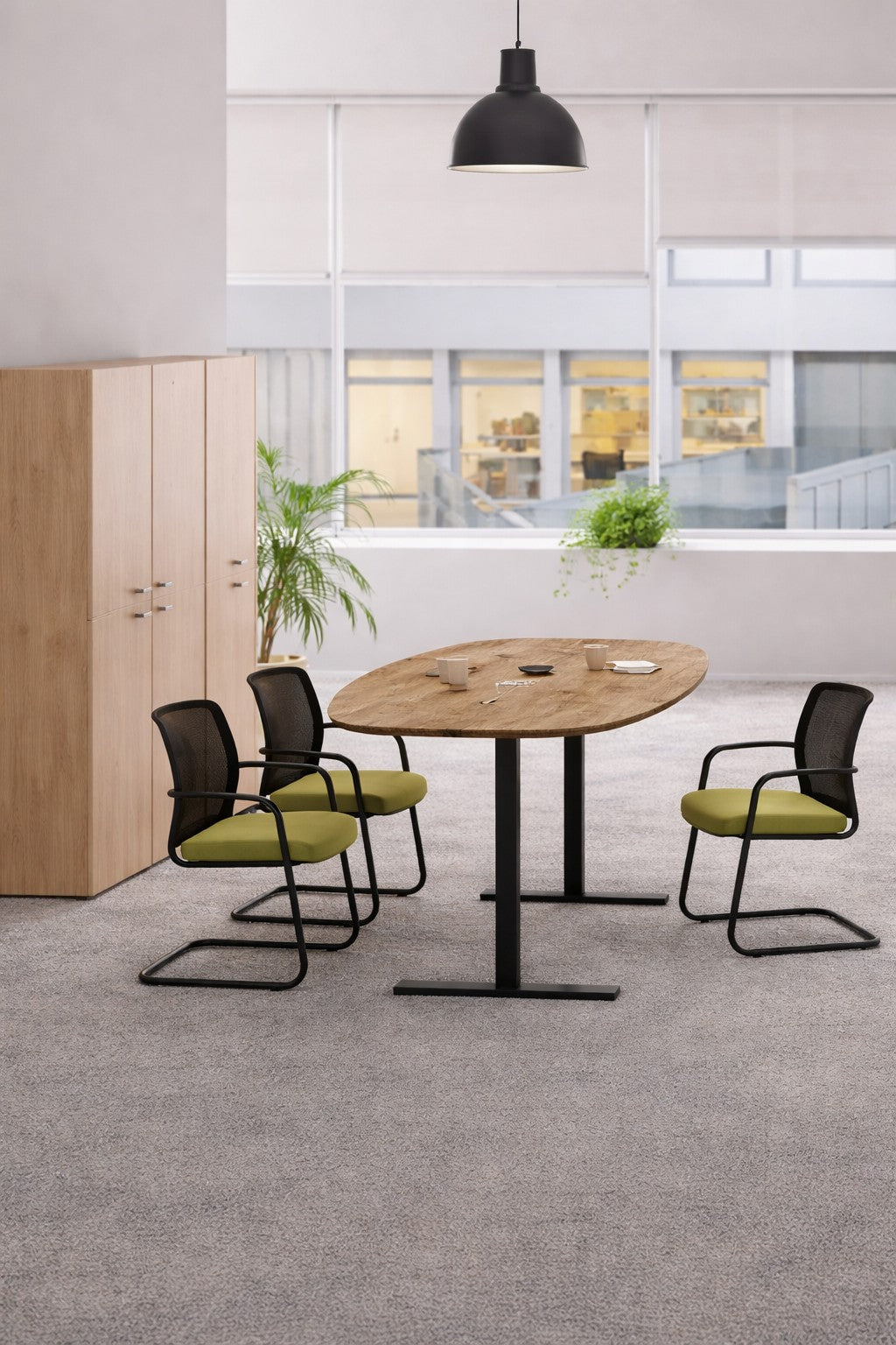 Un bureau moderne avec la Table tonneau électrique Top & Down - 6/8 personnes de Monsieur Bureau comme table de réunion, entourée de trois chaises noires et vertes, de plantes en pot, de hautes armoires en bois, de grandes fenêtres et d'un plafonnier noir au-dessus..#combo_timber_noir