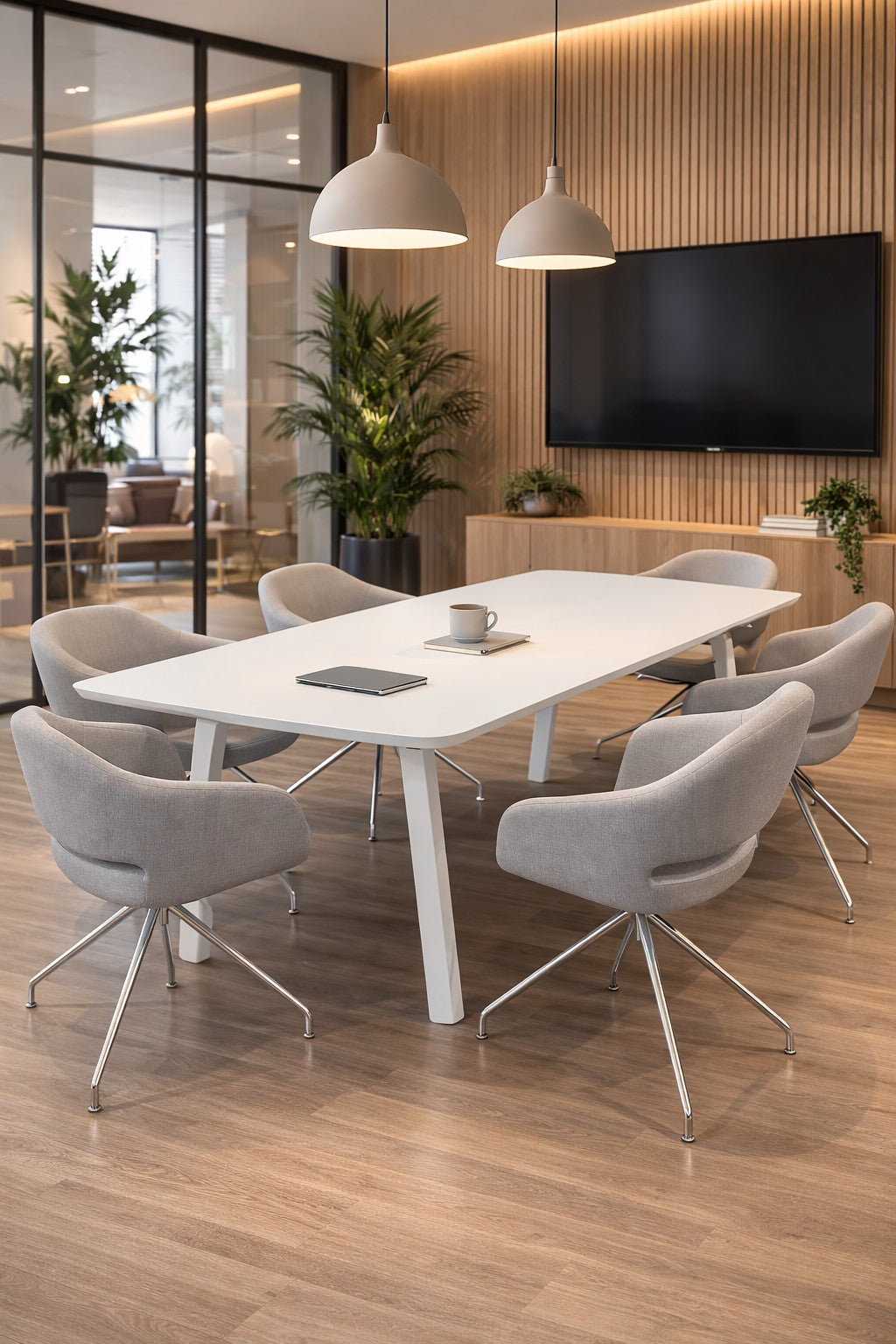 Salle de conférence moderne avec un Monsieur Bureau Table de réunion tonneau ATMOSPHERIC 6 personnes, six chaises grises, une tablette, un mug et un ordinateur portable. Des panneaux muraux en bois, un téléviseur monté, de grandes plantes et des murs en verre complètent cet espace élégant..#combo_blanc_blanc