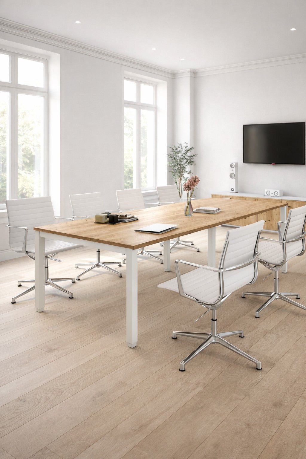 Une salle de conférence moderne dotée de la Table de réunion rectangulaire 6 à 14 personnes Tempo de Monsieur Bureau, de chaises pivotantes blanches, d'un téléviseur à écran plat, de grandes fenêtres, d'un parquet en bois clair et d'une table garnie de fleurs et de fournitures de bureau.#combo_chene_veine_blanc