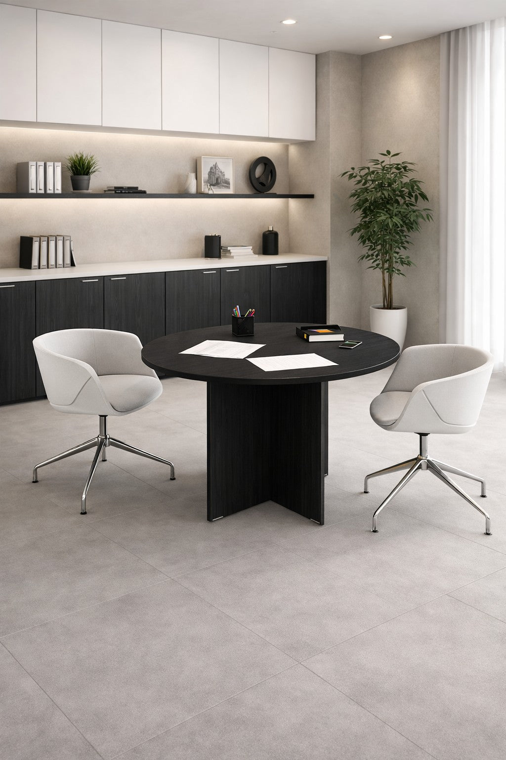 Un bureau moderne avec mobilier bureau, comprenant un Monsieur Bureau Table de réunion Budget ronde Ø120, deux chaises blanches, des papiers épars, des armoires noires, des livres et de la décoration sur des étagères blanches, une plante en pot, et une grande fenêtre avec des rideaux diaphanes.#finitions_frene_noir