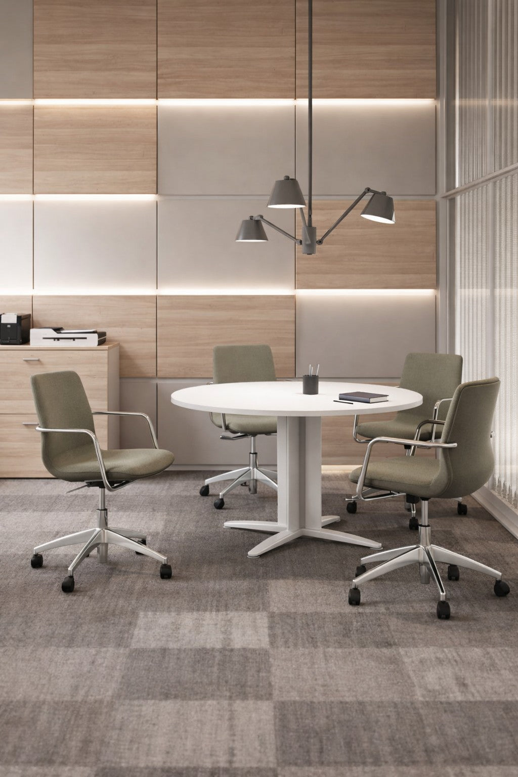 Un espace collaboratif moderne comprenant la Table de réunion ronde Atlas (116 cm) de Monsieur Bureau, quatre chaises de bureau vertes sur roulettes, un plafonnier et des murs en bois beige avec éclairage intégré. Une armoire et une imprimante se trouvent à l'arrière-plan.#finitions_blanc_blanc