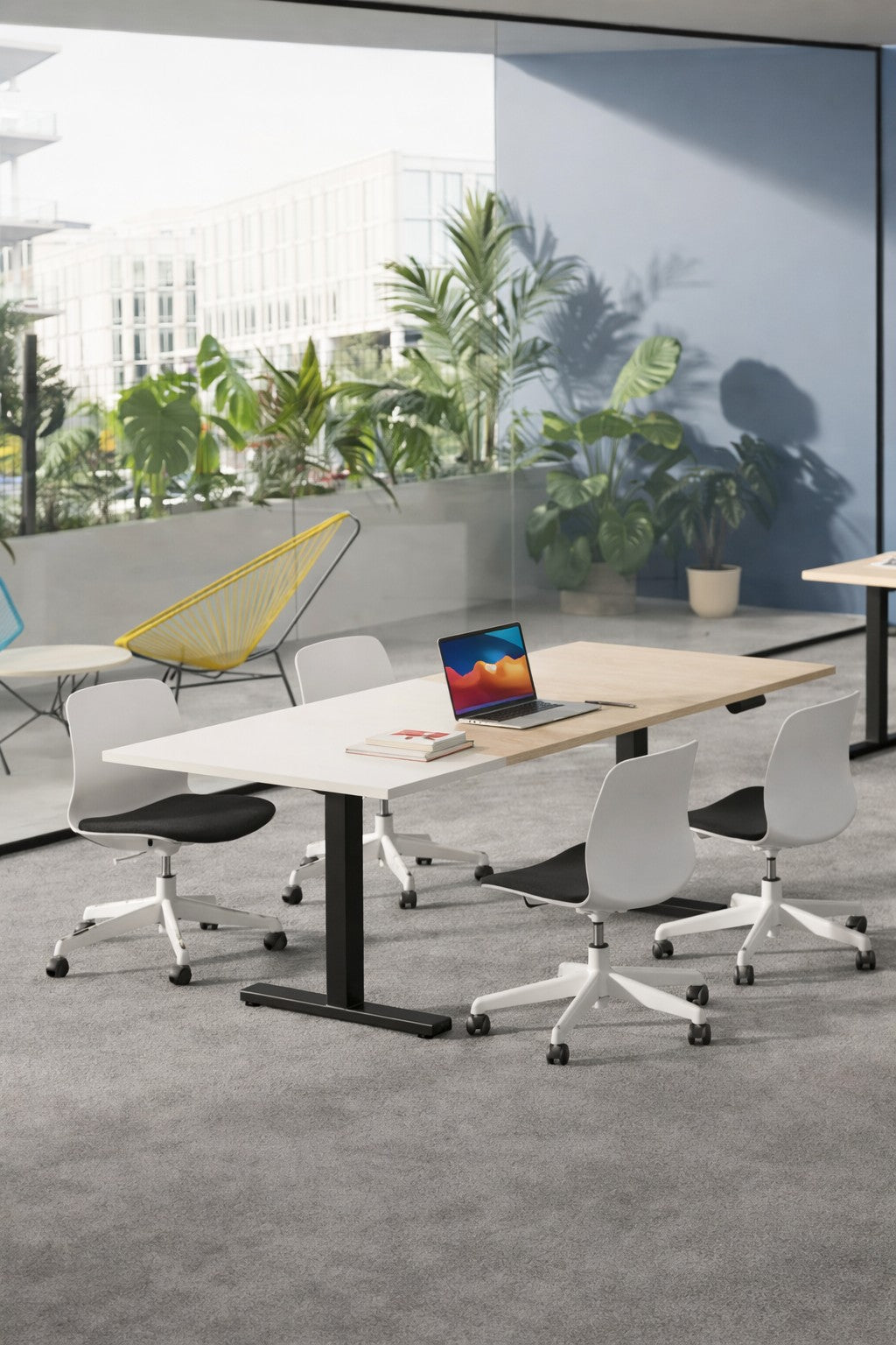 Bureau moderne avec une Table rectangulaire électrique Top & Down 6 à 8 pers. de Monsieur Bureau, quatre chaises blanches sur roulettes, un ordinateur portable ouvert, des livres et des plantes près de grandes fenêtres avec vue sur la ville. Une chaise jaune et d'autres plantes se trouvent à l'extérieur de la paroi vitrée.#combo_blanc_noir