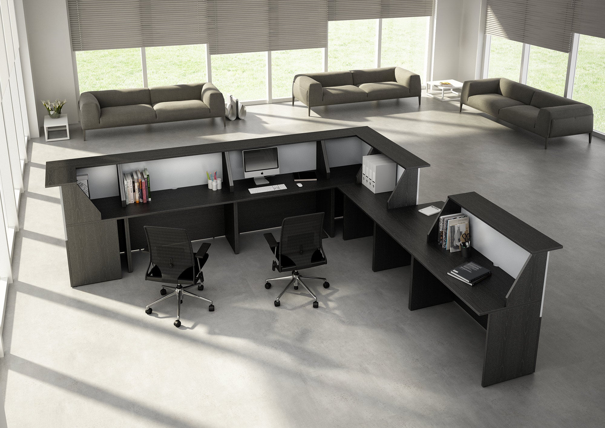 Espace de bureau moderne présentant la grande et sombre Muse à composer banque d'accueil modulable de Monsieur Bureau, associée à trois chaises de bureau noires, des ordinateurs, des livres et des dossiers. Des canapés gris sont installés à l'arrière-plan, près des fenêtres éclairées par le soleil.