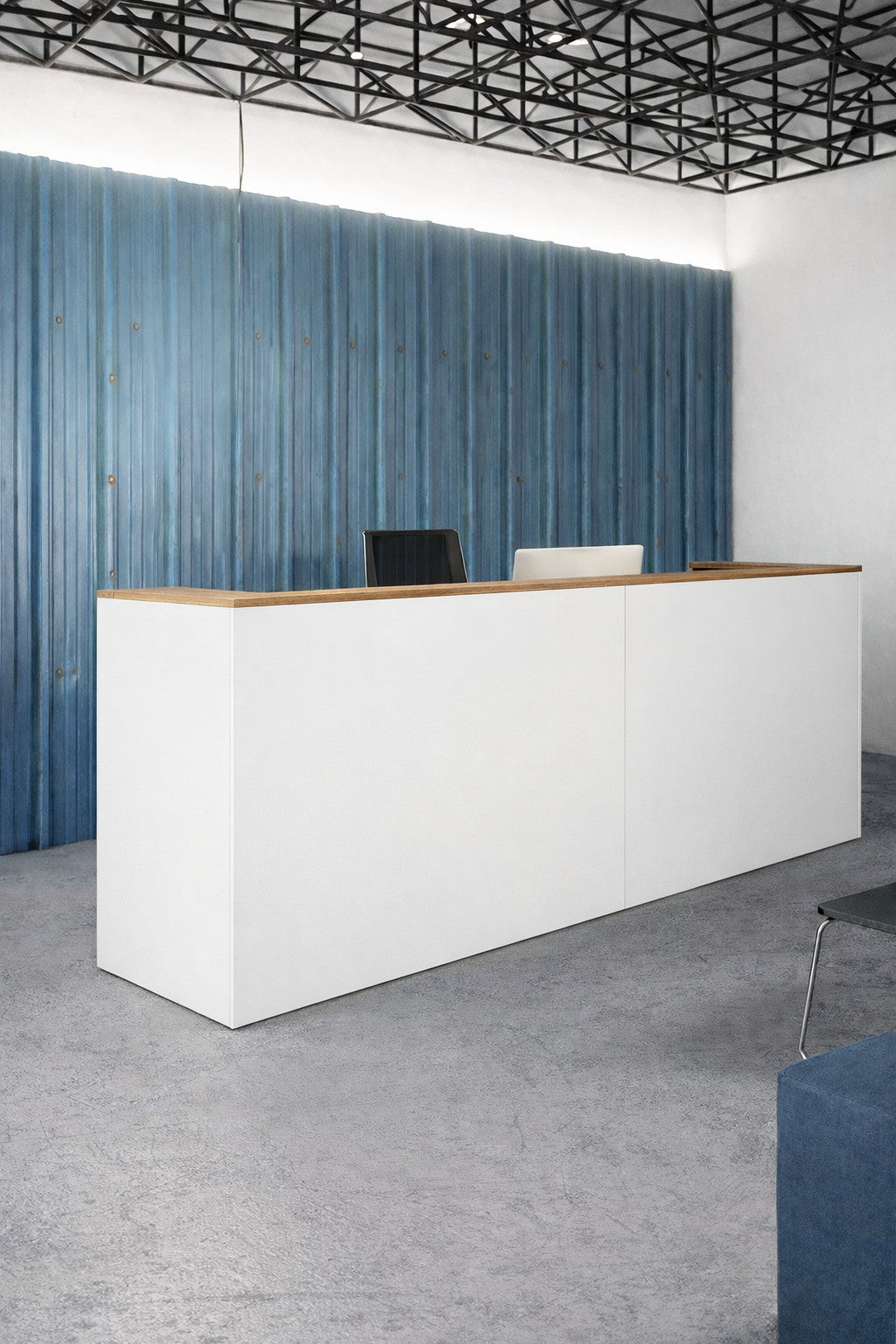 Le Comptoir d'accueil professionnel Monsieur Bureau Delta Pro L145 à L365 est doté d'un plateau en bois, d'une façade blanche et se trouve devant un mur ondulé bleu avec deux chaises derrière lui et un plafond noir géométrique au-dessus.#finitions_blanc_avec_top_Chêne_moyen_199