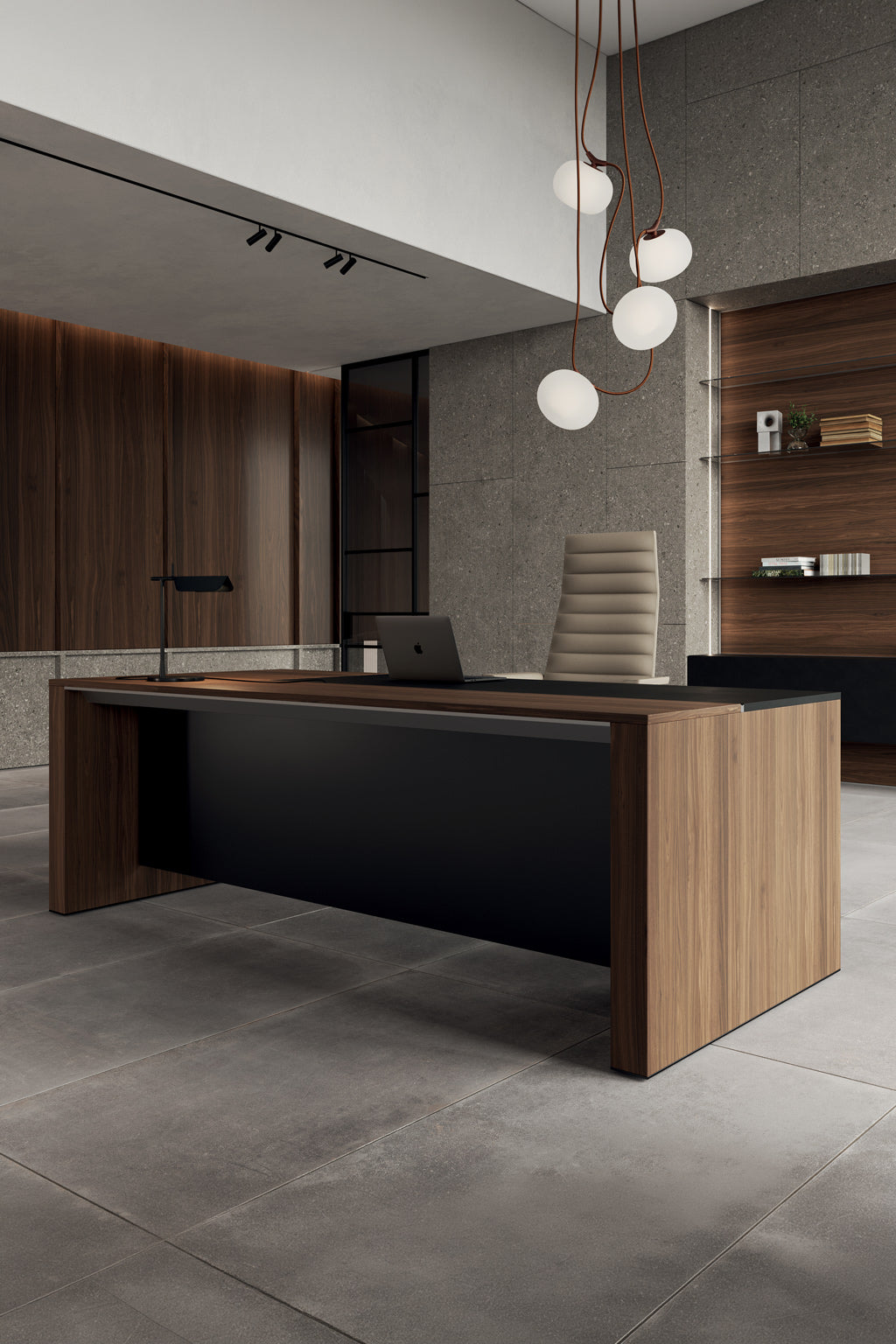 Un bureau moderne avec le Monsieur Bureau Bureau de direction L200 ONO Monolithique en placage de bois, associé à une chaise en cuir, un ordinateur portable, une lampe de bureau, des lampes globe suspendues, des surfaces en pierre grise, des accents en bois et des étagères encastrées.