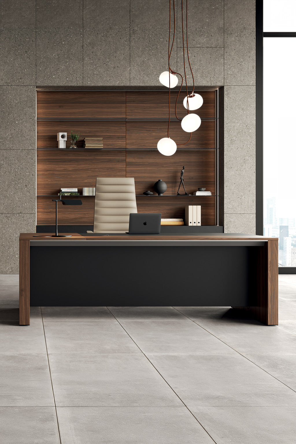 Un bureau moderne avec le Bureau de direction L200 ONO Monolithique - Placage bois de Monsieur Bureau, une chaise beige et un ordinateur portable. Des étagères murales en bois exposent des livres et des objets de décoration. Des suspensions rondes sont suspendues au-dessus des fenêtres avec vue sur la ville.
