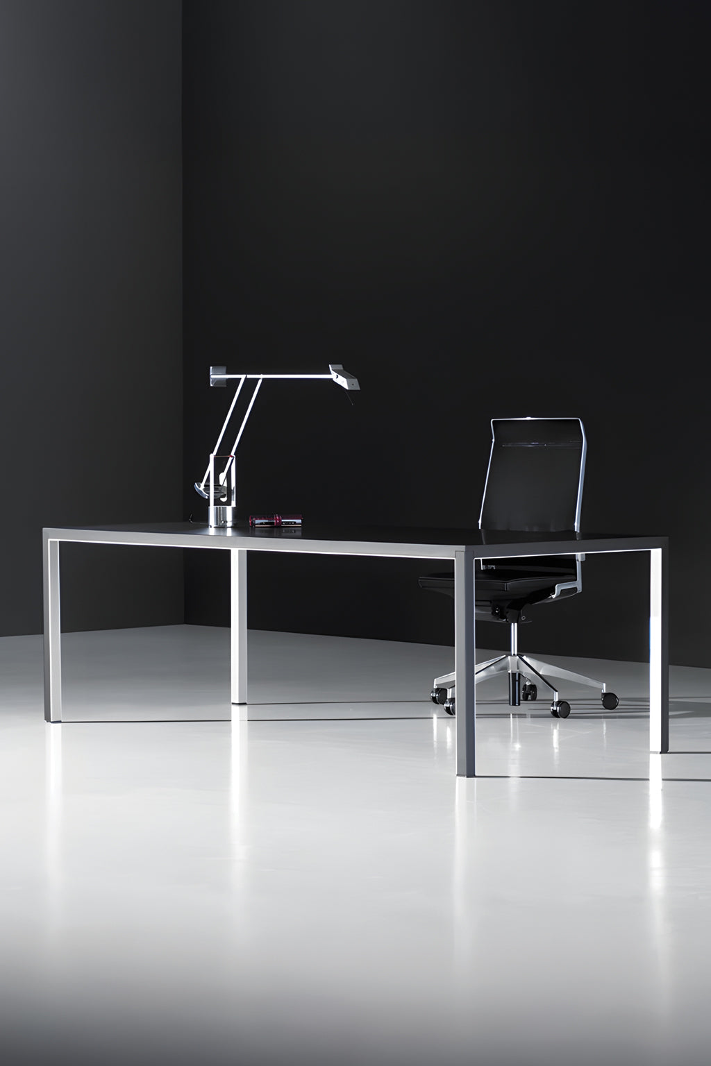 Bureau de direction Nova (L200 x P100 cm) de Monsieur Bureau, associé à une lampe de bureau moderne noire et à une chaise pivotante en maille noire sur un sol clair contre un mur sombre. Un stylo est posé sur le bureau.