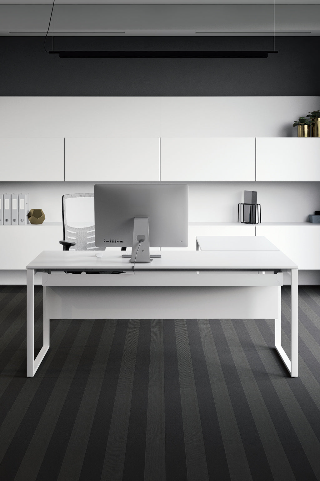 Un bureau moderne avec un Bureau de direction Pop Square avec retour de Monsieur Bureau, comprenant un piètement cadre, un écran d'ordinateur et une chaise. Les armoires et les étagères blanches permettent d'organiser les objets, tandis que le sol à rayures foncées complète le look monochrome.