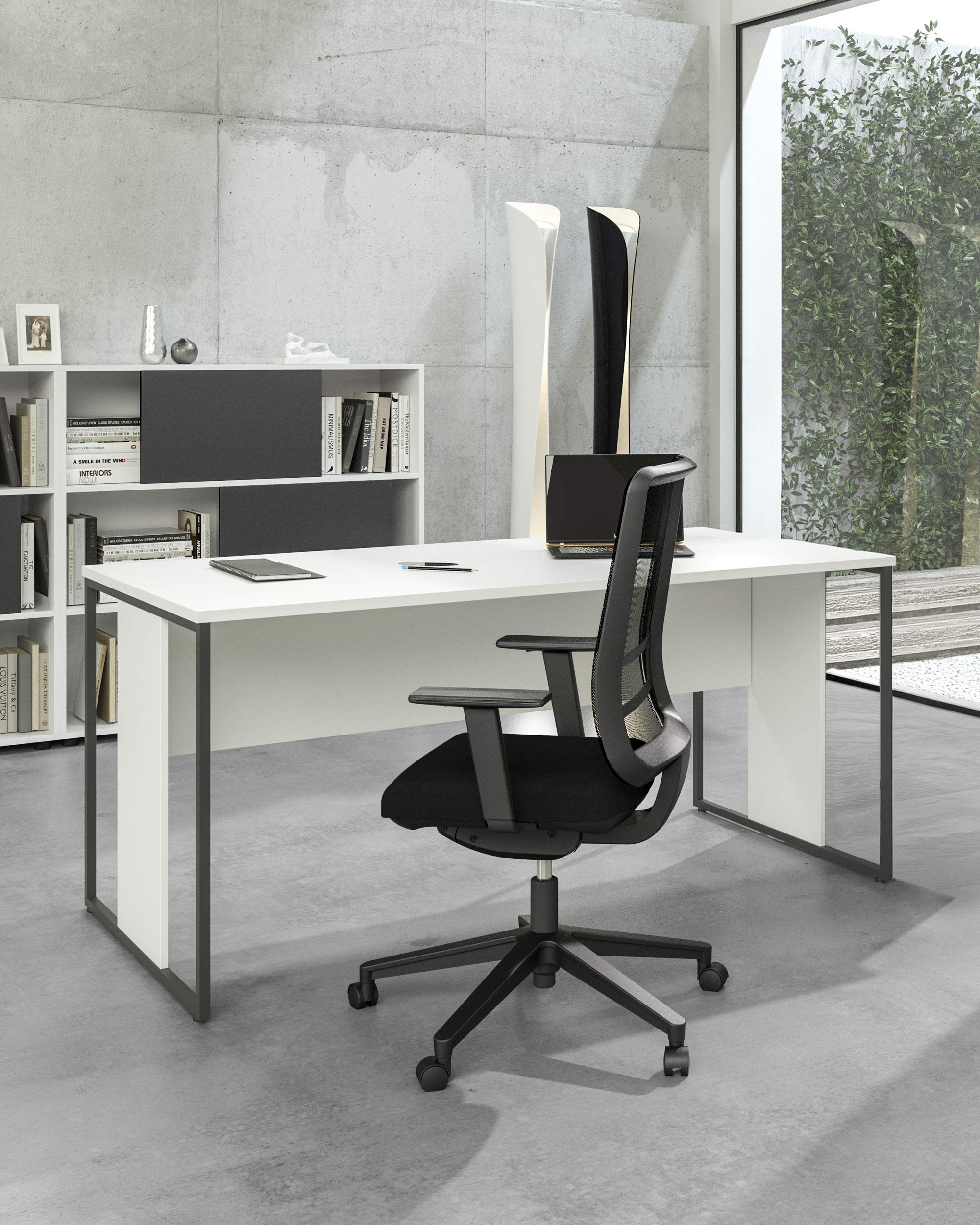 Un bureau moderne avec le Bureau Edge Modulable P80 droit ou angle de Monsieur Bureau, une chaise de bureau noire, une étagère ouverte avec des livres, un ordinateur portable, une grande fenêtre avec de la verdure, des murs en béton et un design italien minimaliste.#combo_blanc_anthracite_mat_bureau_droit