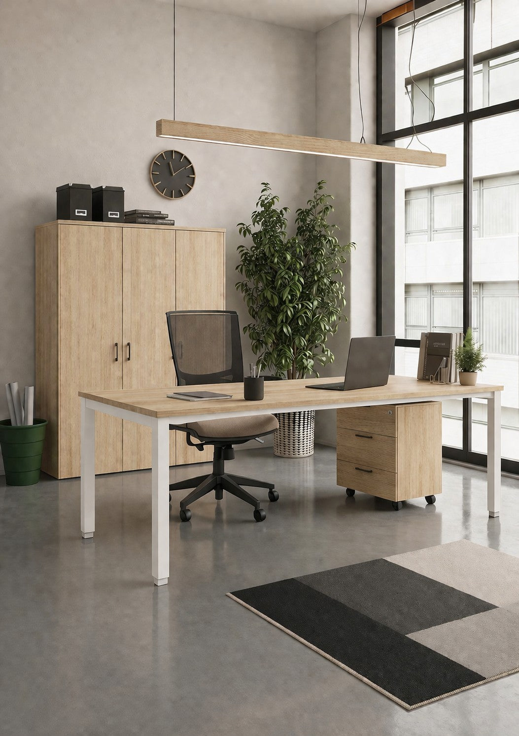 Le bureau moderne comprend le bureau professionnel individuel Monsieur Bureau Tempo P60 cm, une chaise de bureau noire, deux ordinateurs portables, une armoire, une horloge murale, une plante haute, de grandes fenêtres avec de la lumière naturelle et un tapis géométrique recouvrant le sol.