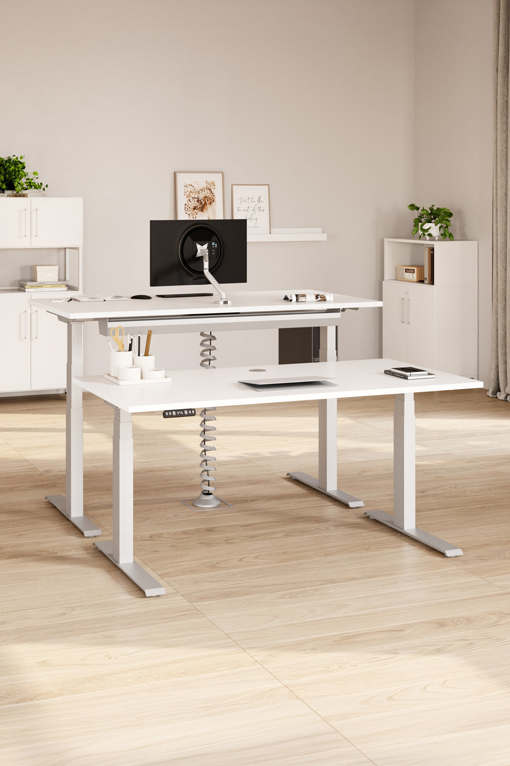 Bureau moderne avec deux bureaux Monsieur Bureau Desk Up (L120/160/180 cm), chacun équipé d'un moniteur et d'un ordinateur portable. Des planchers en bois clair, des armoires blanches, des plantes et des œuvres d'art encadrées complètent cet espace de travail ergonomique, propre et minimaliste.#combo_blanc_blanc