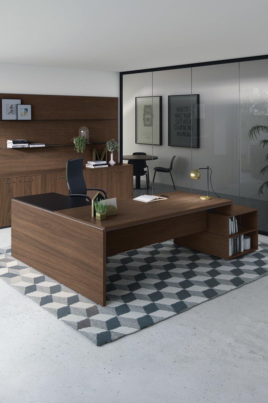 Le Bureau de direction Asset avec retour et rangement par Monsieur Bureau comprend un bureau spacieux en bois dans la finition de l'entrée, associé à une chaise de bureau noire, des plantes décoratives, une lampe de bureau, un tapis géométrique, des armoires en bois, des murs en verre, des objets d'art et une table d'appoint.