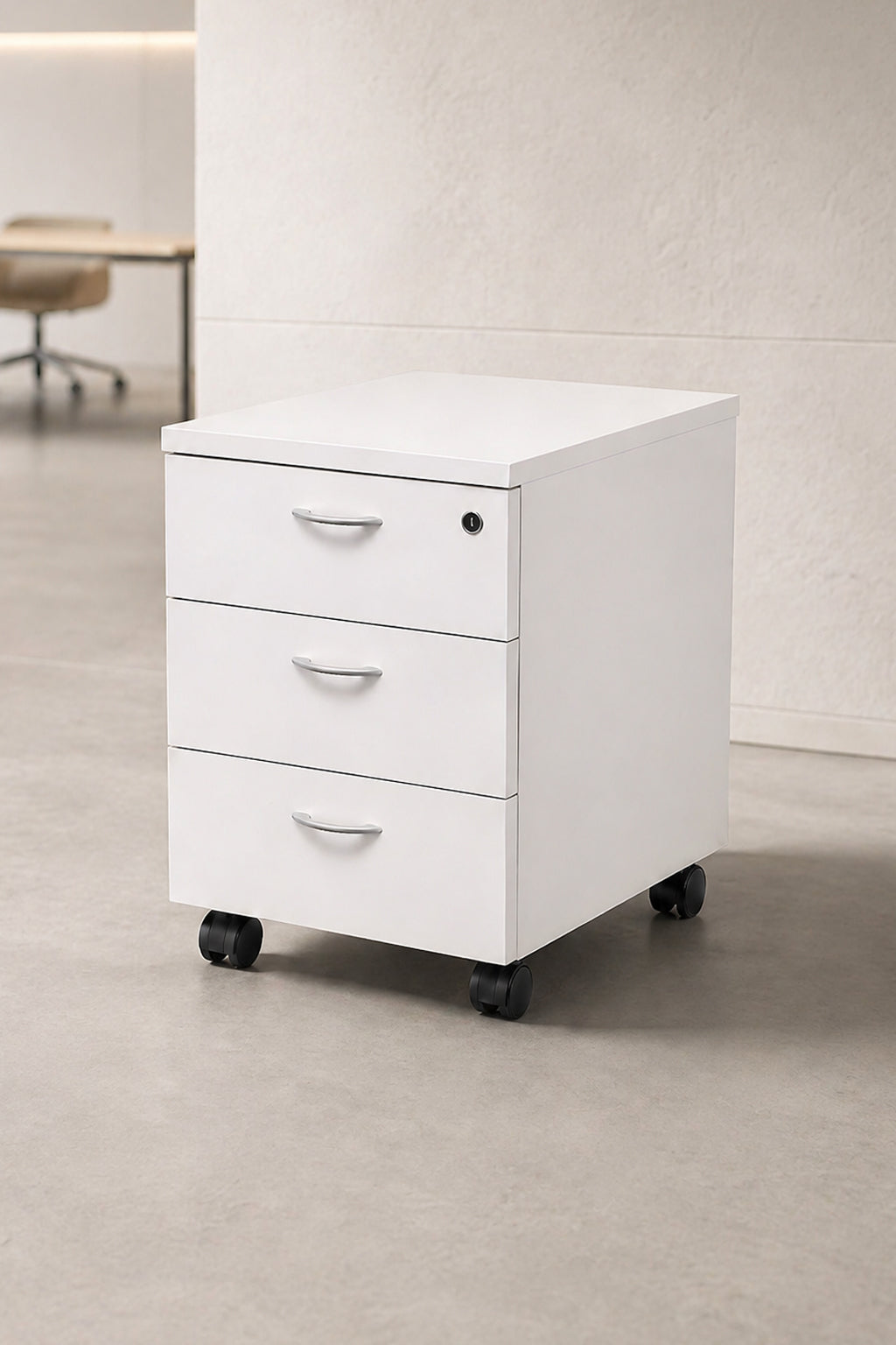 Un Caisson mobile Budget / Effect 2 ou 3 tiroirs de Monsieur Bureau, doté de trois tiroirs et de roues noires, est posé sur un sol gris clair dans un bureau minimaliste. Un bureau et une chaise à l'arrière-plan offrent une configuration idéale pour le rangement intelligent.