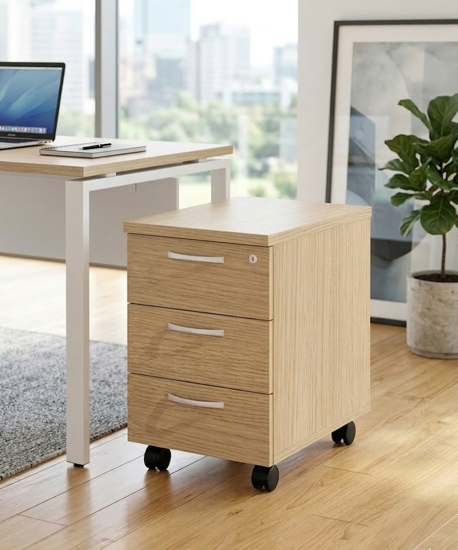 A Monsieur Bureau Caisson Mobile Curvy / Express+ à 2 ou 3 tiroirs, en bois clair et sur roulettes, est placé près d'un bureau blanc moderne dans un bureau lumineux avec de grandes fenêtres, un ordinateur portable et une plante verte.#combo_3_tiroirs_chene
