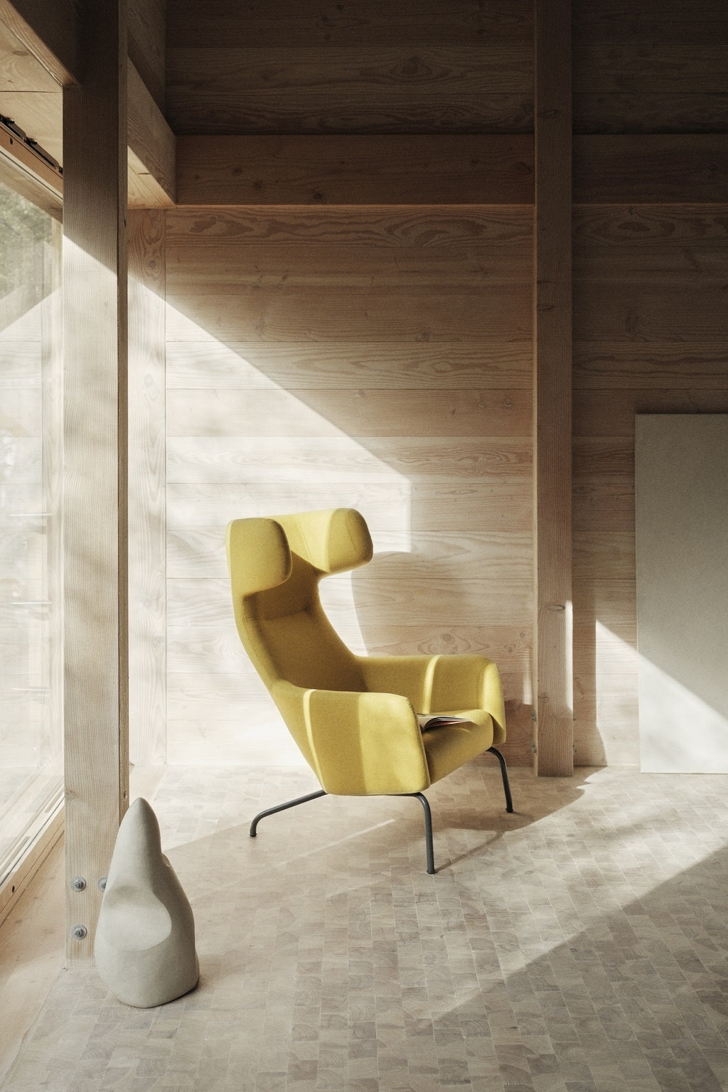 Une pièce moderne aux murs et au sol en bois clair présente le dossier Fauteuil lounge Fjord haut de Busk+Hertzog pour Monsieur Bureau en jaune vif, incarnant un design scandinave par la grande fenêtre.#finitions_jaune