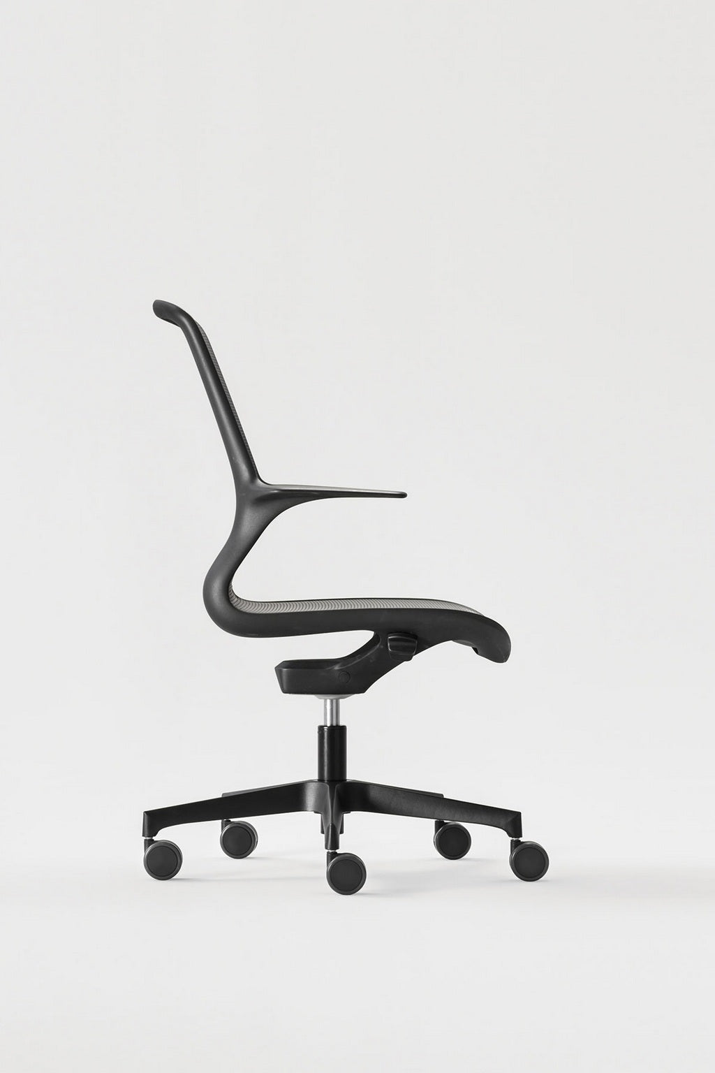 Le Monsieur Bureau Fauteuil de bureau professionnel Nate - Résille noire est un siège de bureau moderne de couleur noire avec un haut dossier en maille et une assise incurvée sur un piètement à cinq roues, présenté de profil sur un fond blanc uni.