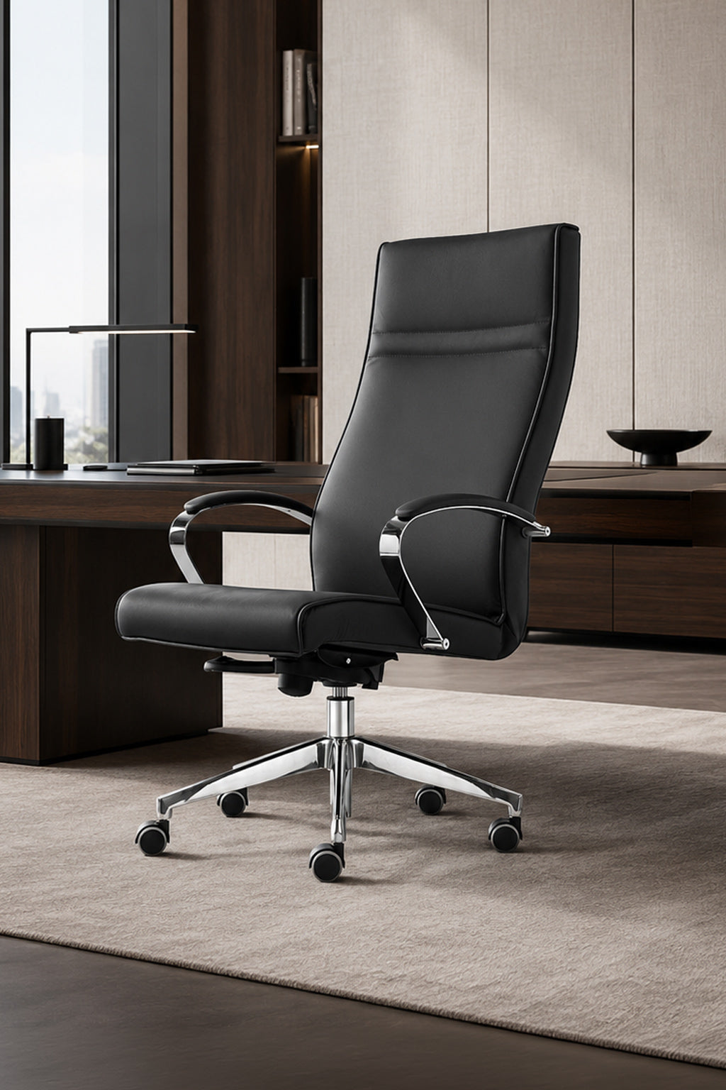 Le Fauteuil de direction Venus cuir haut dossier design de Monsieur Bureau, avec des accoudoirs chromés et une base à roulettes, est posé sur un tapis beige dans un bureau élégant avec des meubles en bois foncé et de grandes fenêtres.