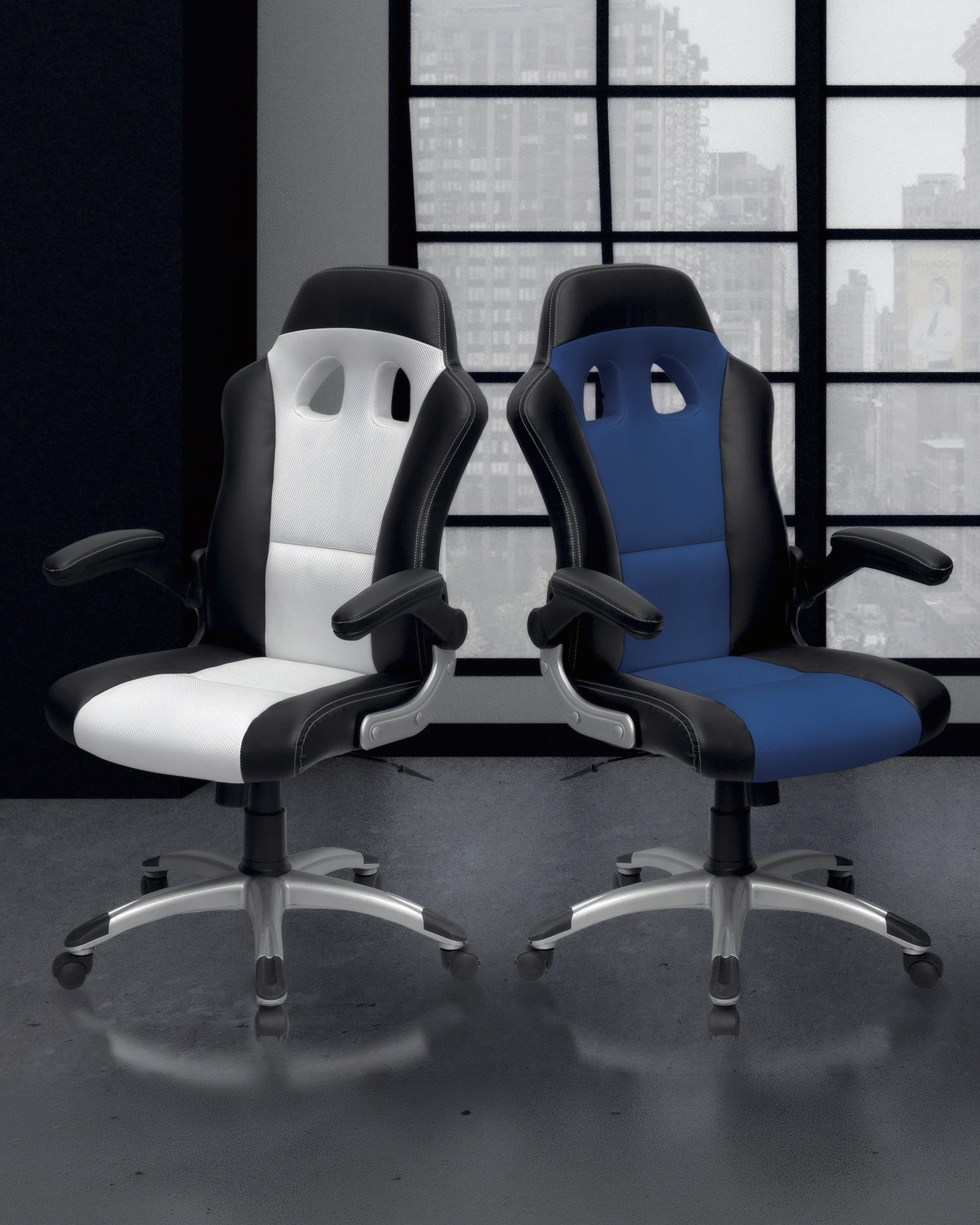 Deux Fauteuil Gamer Racing Geek de Monsieur Bureau, l'un en blanc et noir et l'autre en bleu et noir, se côtoient devant de grandes fenêtres avec vue sur la ville. Livraison rapide disponible.