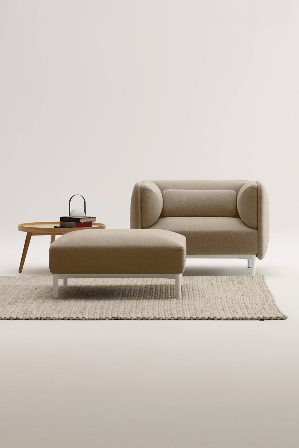 Un salon moderne présente le Monsieur Bureau Fauteuil d'accueil modulaire Aurea en marron avec un ottoman, une table d'appoint ronde en bois avec des livres et un sac, le tout sur un tapis beige texturé sur un fond uni.#finitions_beige446