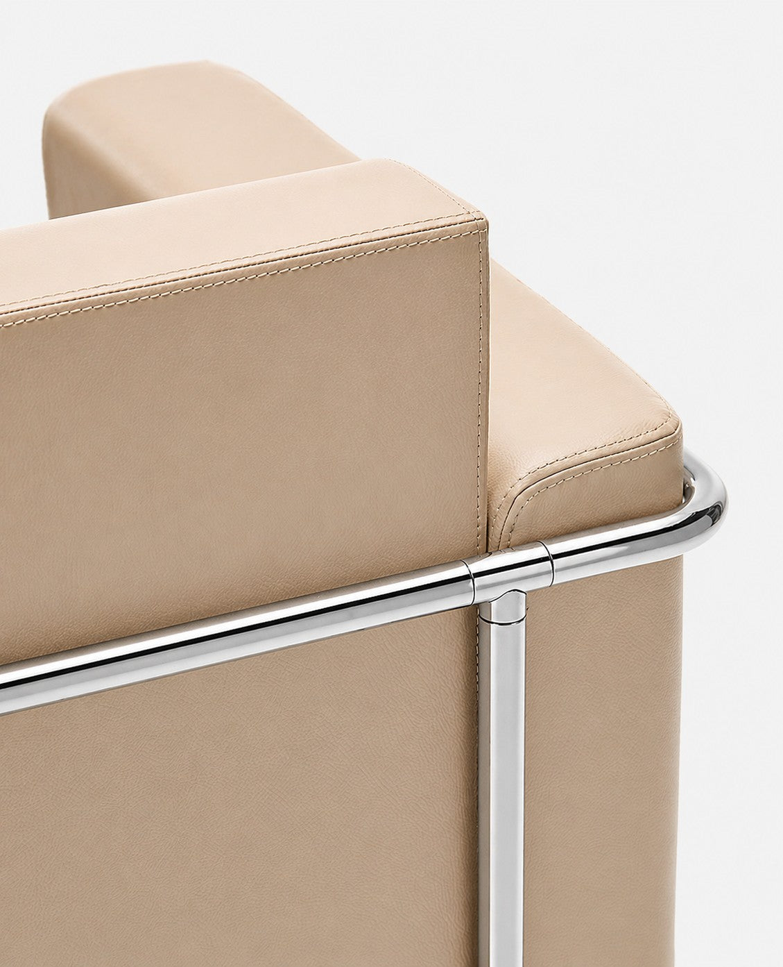 Gros plan sur le Fauteuil d'accueil Matis en simili-cuir de Monsieur Bureau, doté d'un revêtement en similicuir lisse et d'un cadre chromé, mettant en valeur ses lignes épurées et son design minimaliste - idéal pour tout espace d'accueil.
