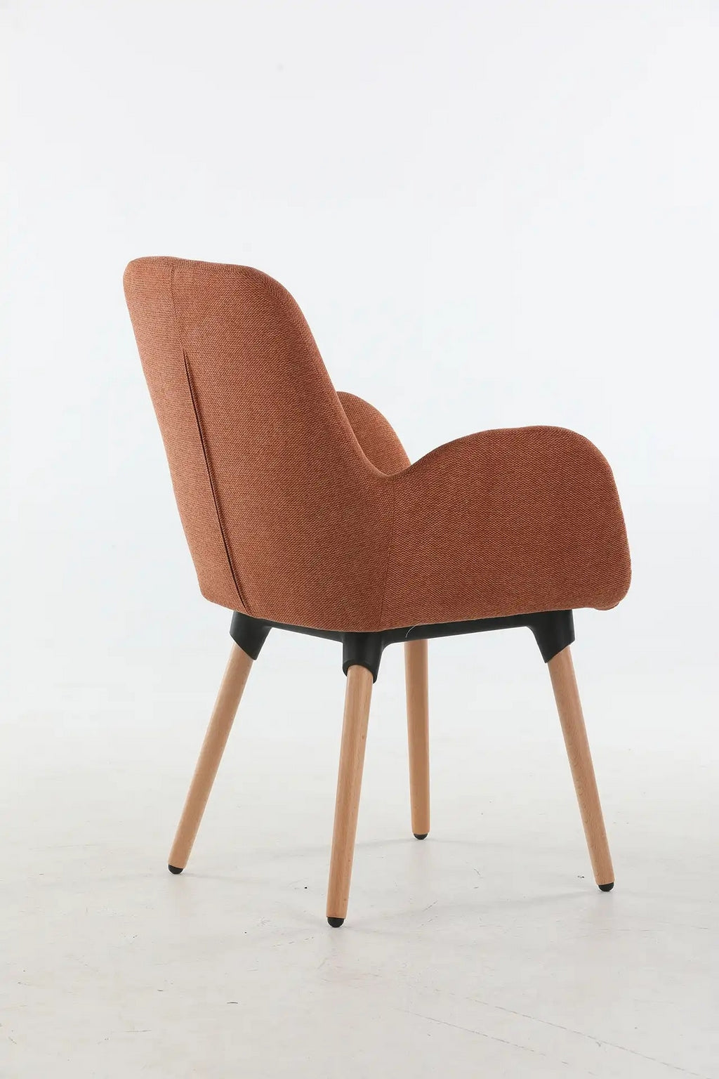 Le Fauteuil d'accueil et réunion Shino de Monsieur Bureau se caractérise par une assise courbée et rembourrée de couleur rouille, des pieds en bois angulaires et un cadre noir, sur un fond blanc uni.