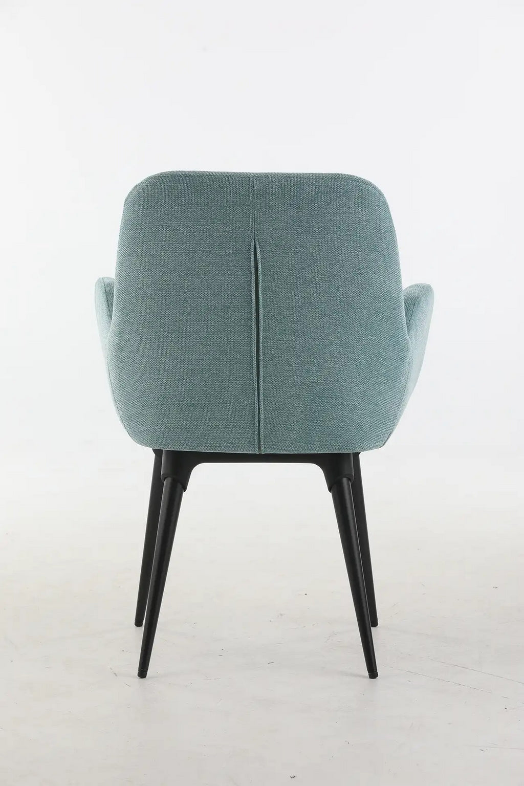 Le Fauteuil d'accueil et réunion Shino de Monsieur Bureau se caractérise par un revêtement bleu clair, des pieds métalliques angulaires noirs et une couture verticale au niveau du dos, le tout sur un fond blanc uni.