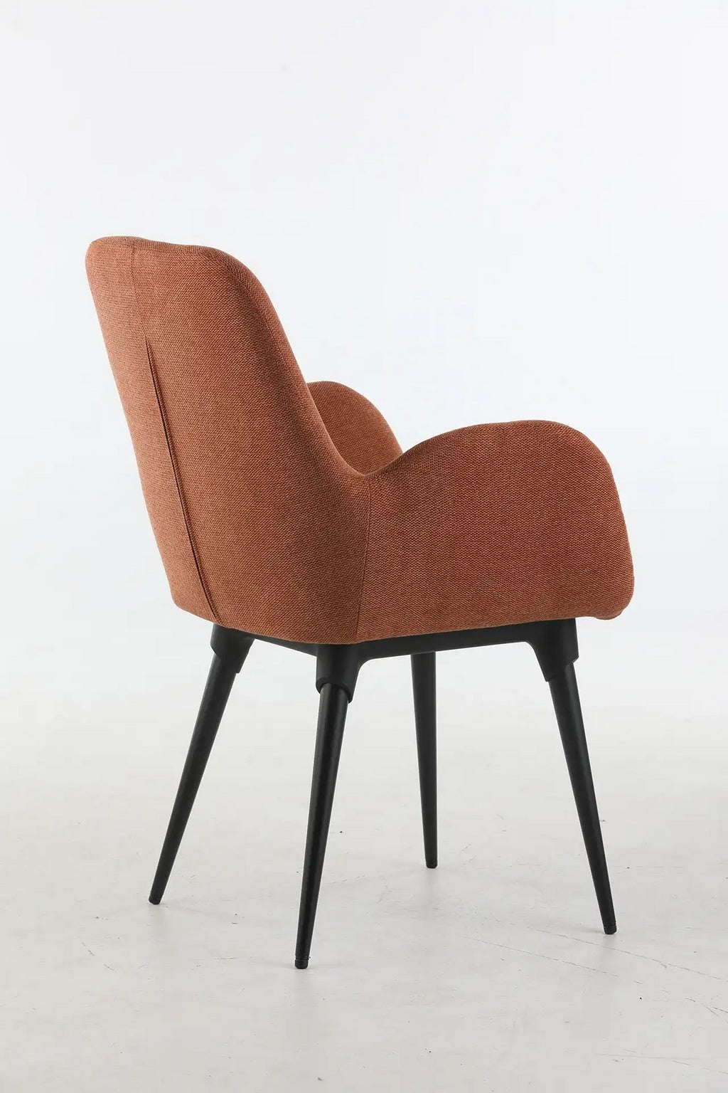 Le Fauteuil d'accueil et réunion Shino de Monsieur Bureau se caractérise par un tissu de couleur rouille et quatre pieds métalliques angulaires noirs, vus de l'arrière sur un fond blanc uni.