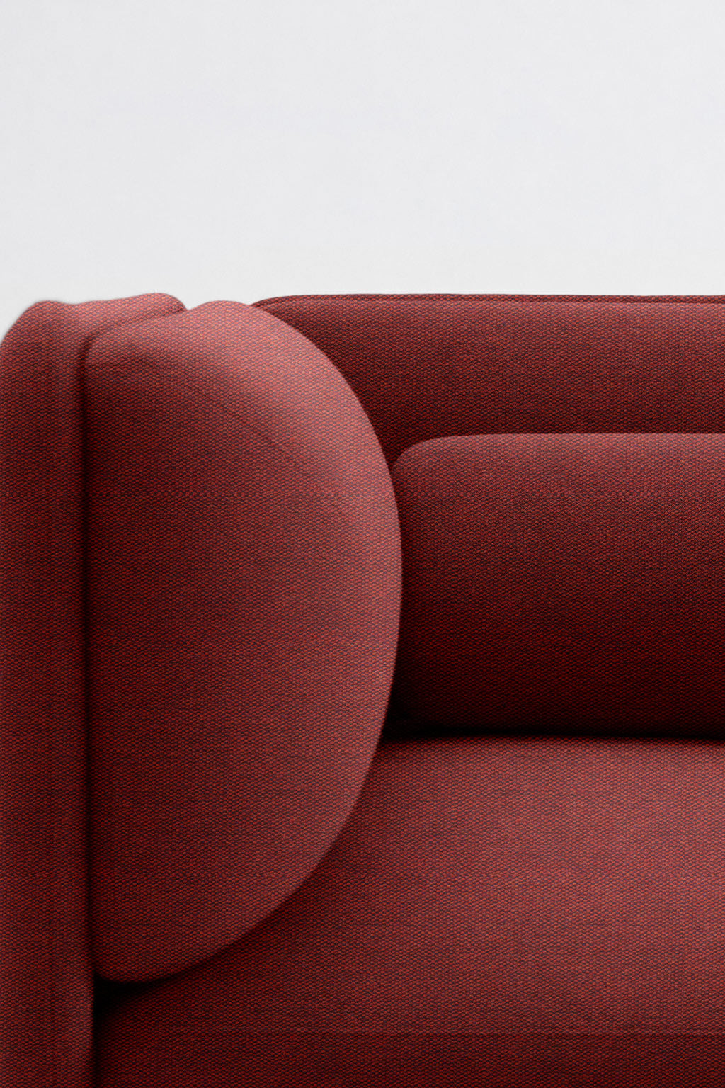 Gros plan sur le côté gauche du Fauteuil d'accueil modulaire Aurea de Monsieur Bureau, avec ses coussins géométriques rouges et arrondis et son design minimaliste sur fond blanc uni.#finitions-terracotta