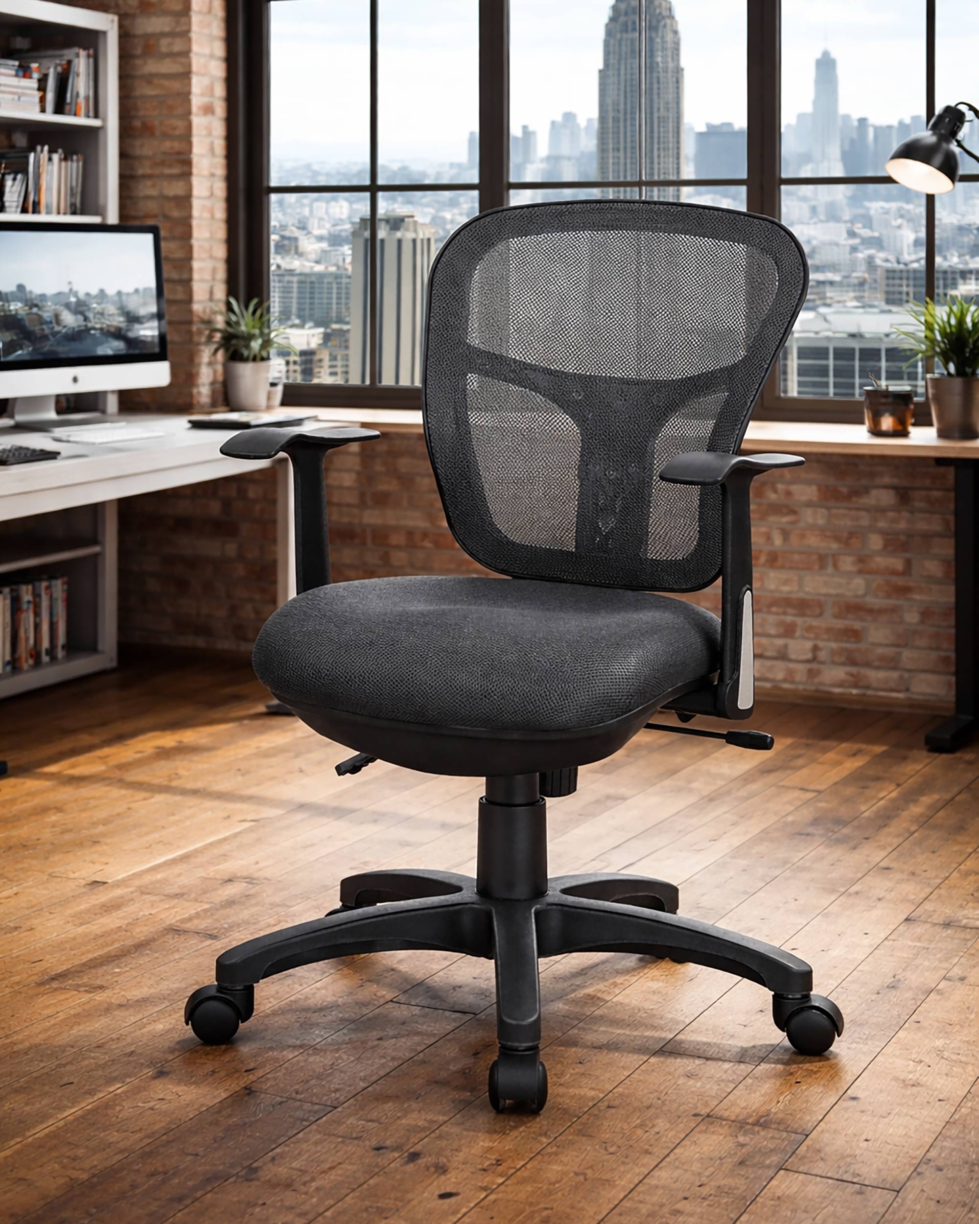 Le Fauteuil Aries dossier résille et soutien lombaire de Monsieur Bureau, équipé d'accoudoirs et de roulettes, assure confort professionnel dans un bureau moderne avec parquet, grandes fenêtres et vue sur la ville.