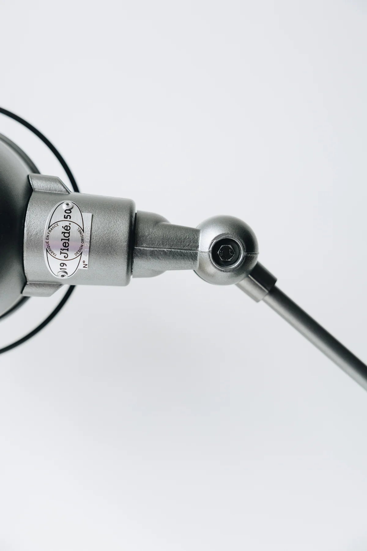 Gros plan sur une Lampe de bureau articulée métallique design Signal de Monsieur Bureau, dont le joint et l'étiquette sont visibles, mettant en valeur son design industriel sur un fond blanc uni.
