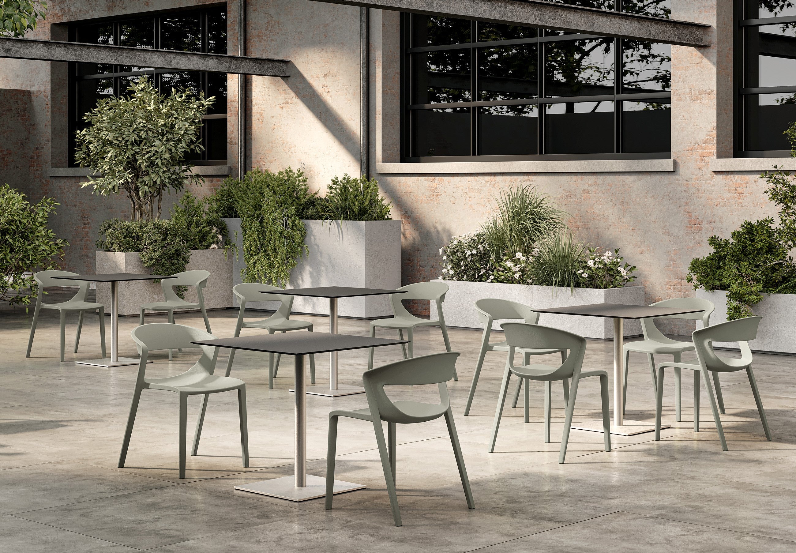 Terrasse extérieure avec plusieurs tables modernes et vides et le Lot de 2 chaises monobloc empilables Kika Polypropylène de Monsieur Bureau sur un sol en béton, entouré de verdure - idéal mobilier de collectivité.