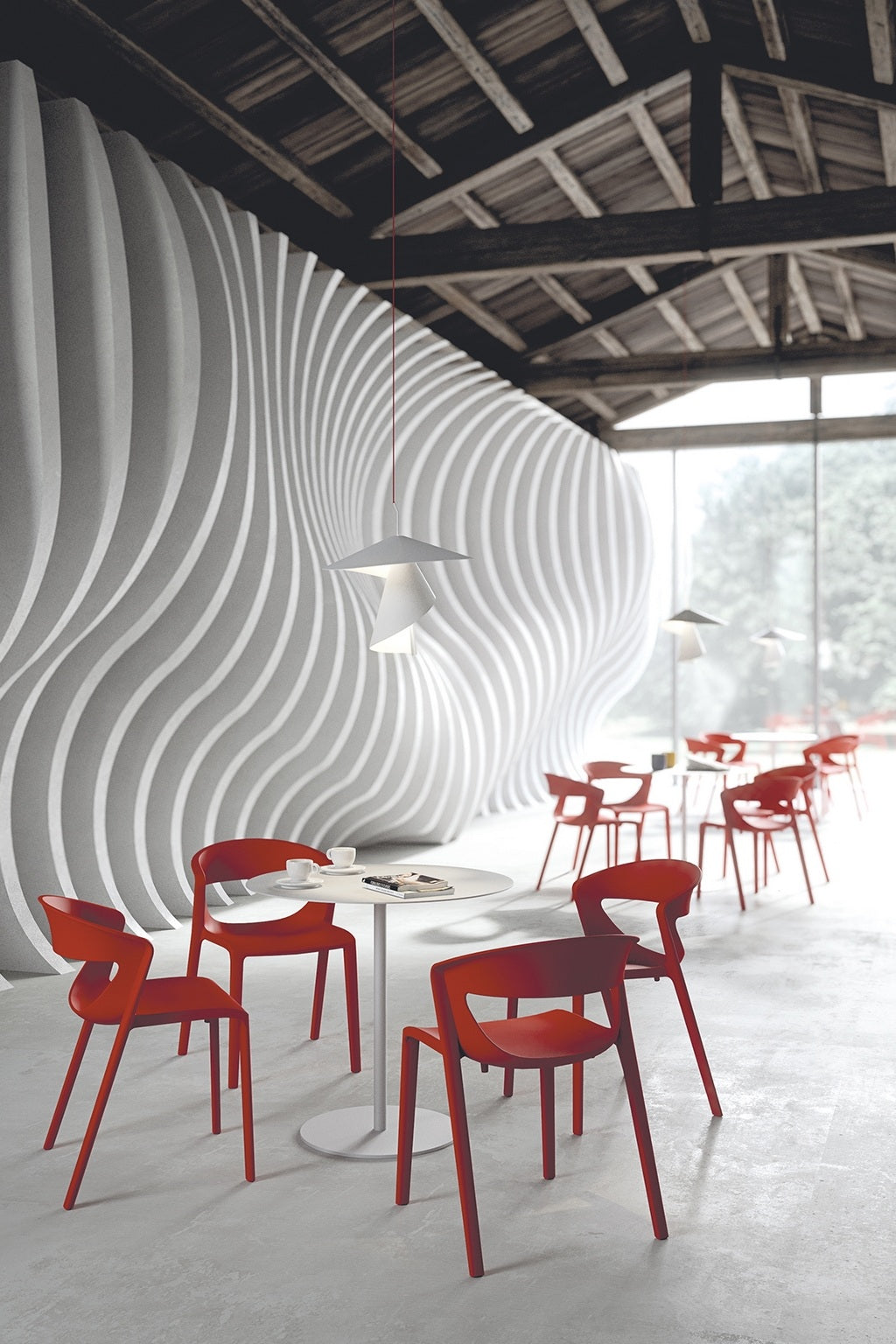 Un café moderne avec Lot de 2 chaises monobloc empilables Kika Polypropylène rouge de Monsieur Bureau, des tables rondes blanches, des panneaux muraux ondulés, de grandes fenêtres et un plafond en bois apparent.