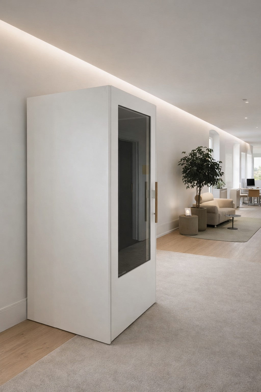 Un bureau ouvert moderne présente la cabine téléphonique acoustique NO SOUND Standard 1 personne de Monsieur Bureau, blanche et élégante, avec une porte en verre, placée à côté de canapés beiges et d'une grande plante en pot, sous un éclairage doux et indirect.