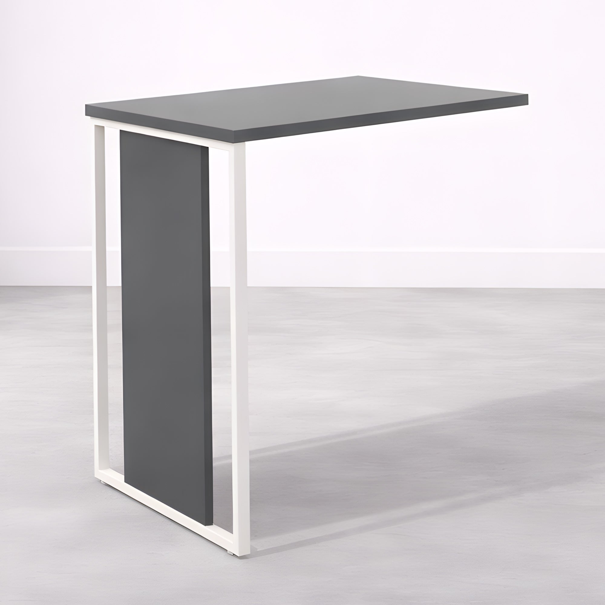 Le Bureau Edge Modulable P80 droit ou angle de Monsieur Bureau, composé d'un plateau rectangulaire gris foncé et d'un panneau vertical assorti sur un cadre en métal blanc, est posé sur un sol gris clair contre un mur blanc.#combo_anthracite_blanc_mat_retour_seul